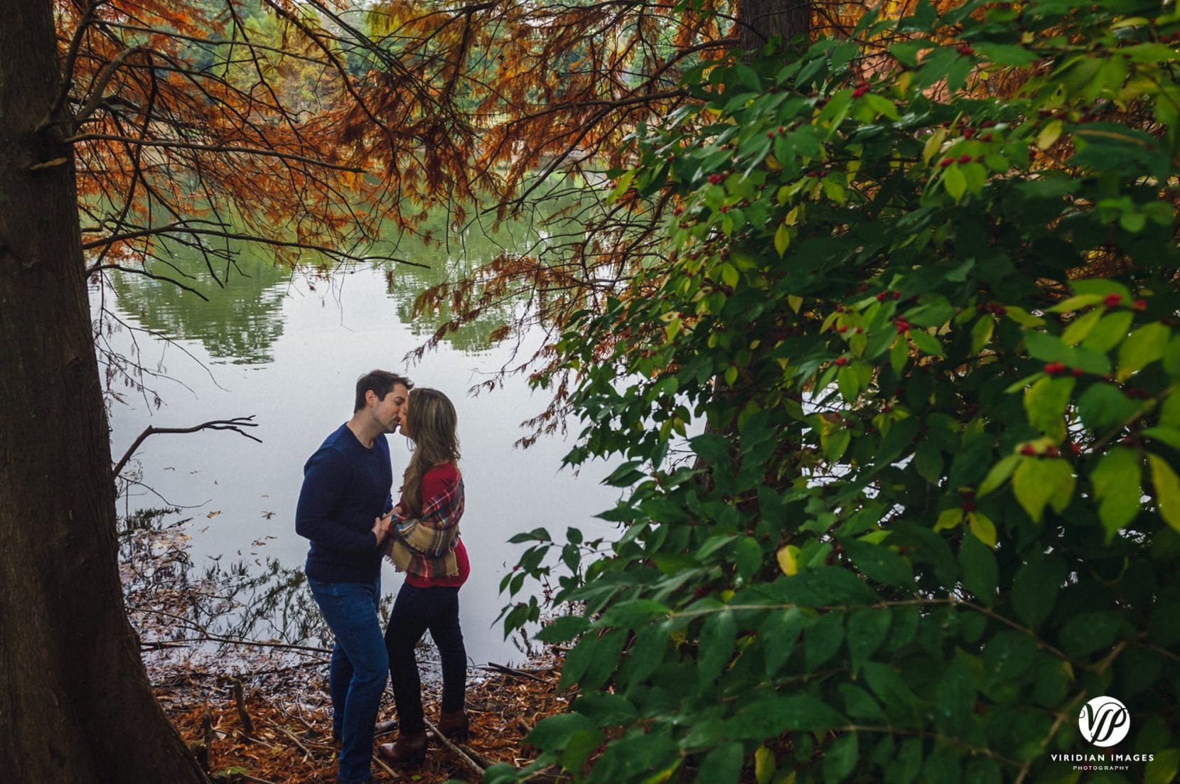 couple kissing by lake at piedmont park engagement photo