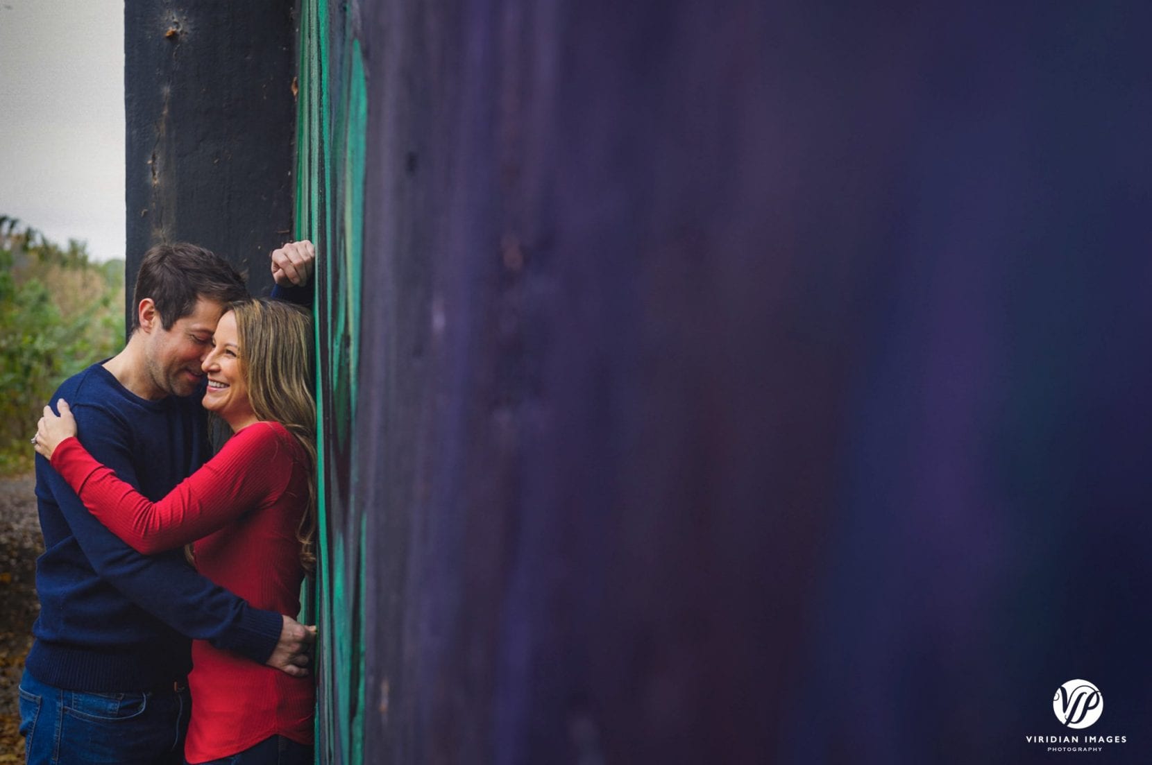 couple embrace and laugh near mural at piedmont park