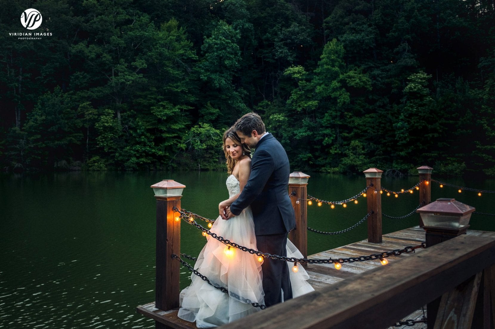 romantic portrait of bride and groom on dock at dusk