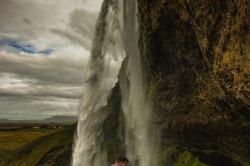 bride and groom kissing under waterfall in iceland