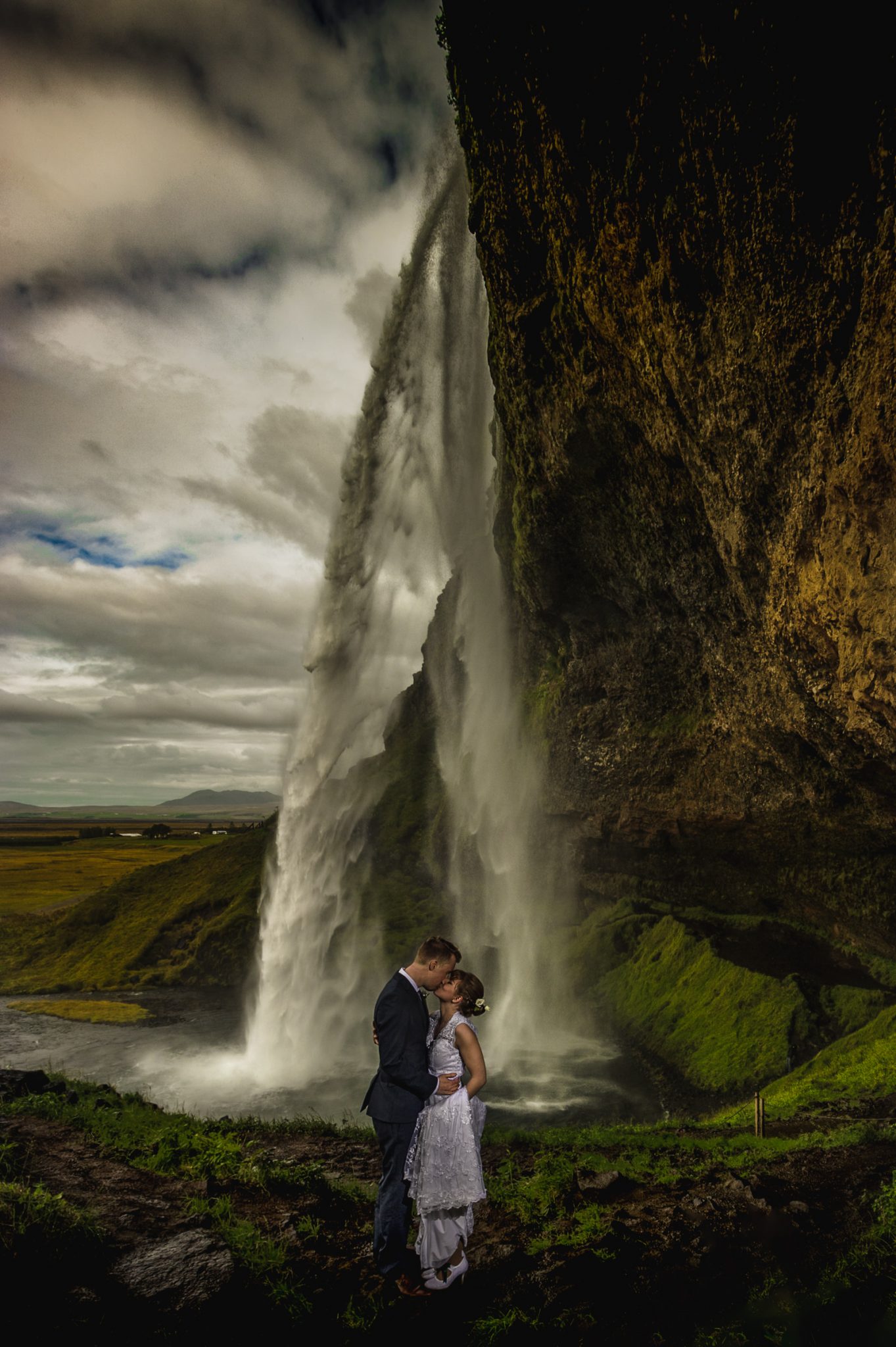 bride and groom kissing under waterfall in iceland