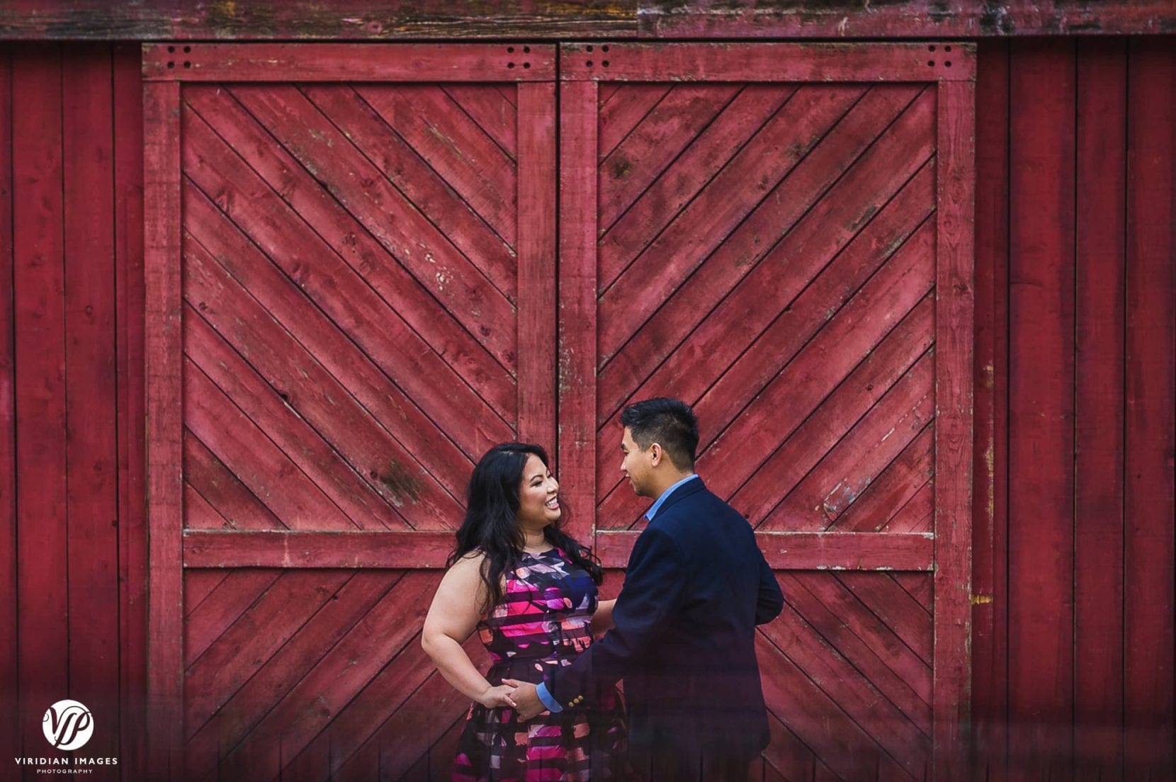 couple swaying front of red barn door in stone mountain park engagement photo