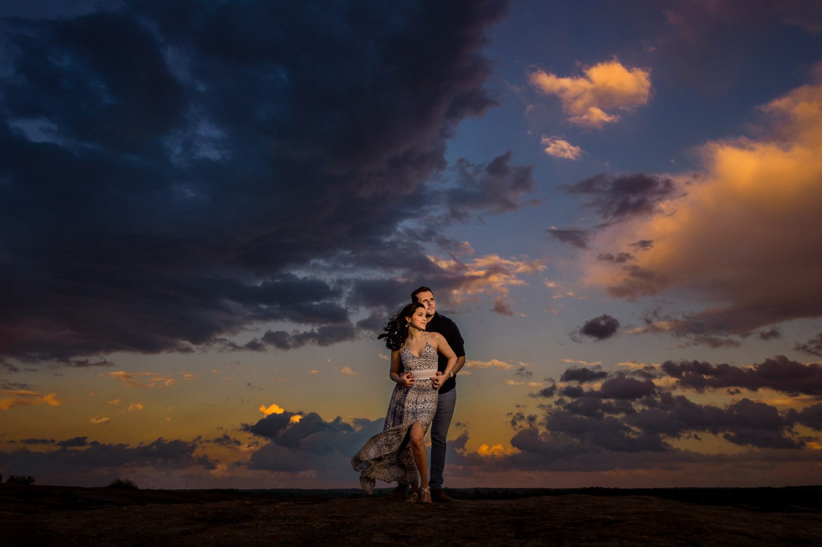 couple looking off distance at sunset top of mountain storm clouds
