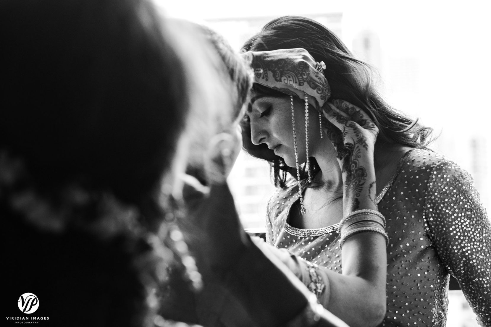 mom puts bridal jewelry on bride