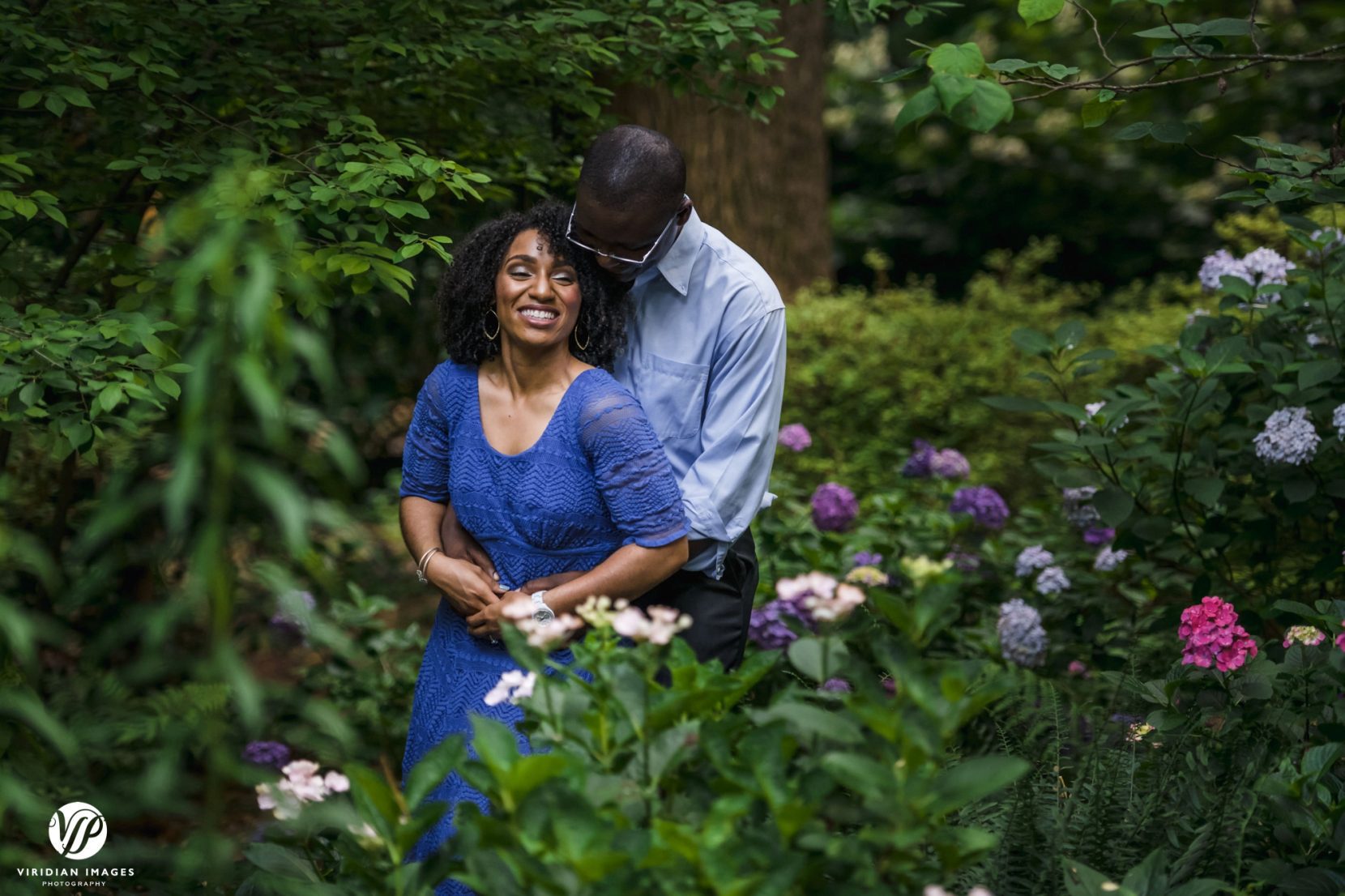 couple in front of flower bushes laughing