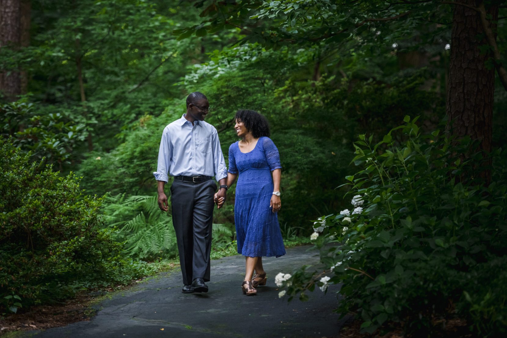 couple walking down park path smiling at each other