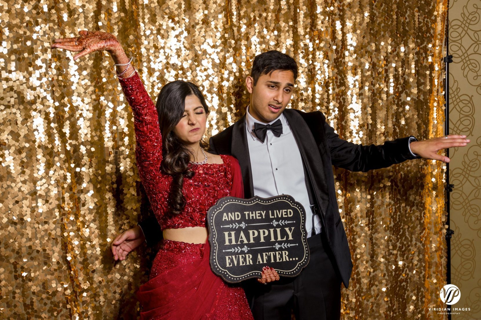 couple posing with gold sequin backdrop and sign