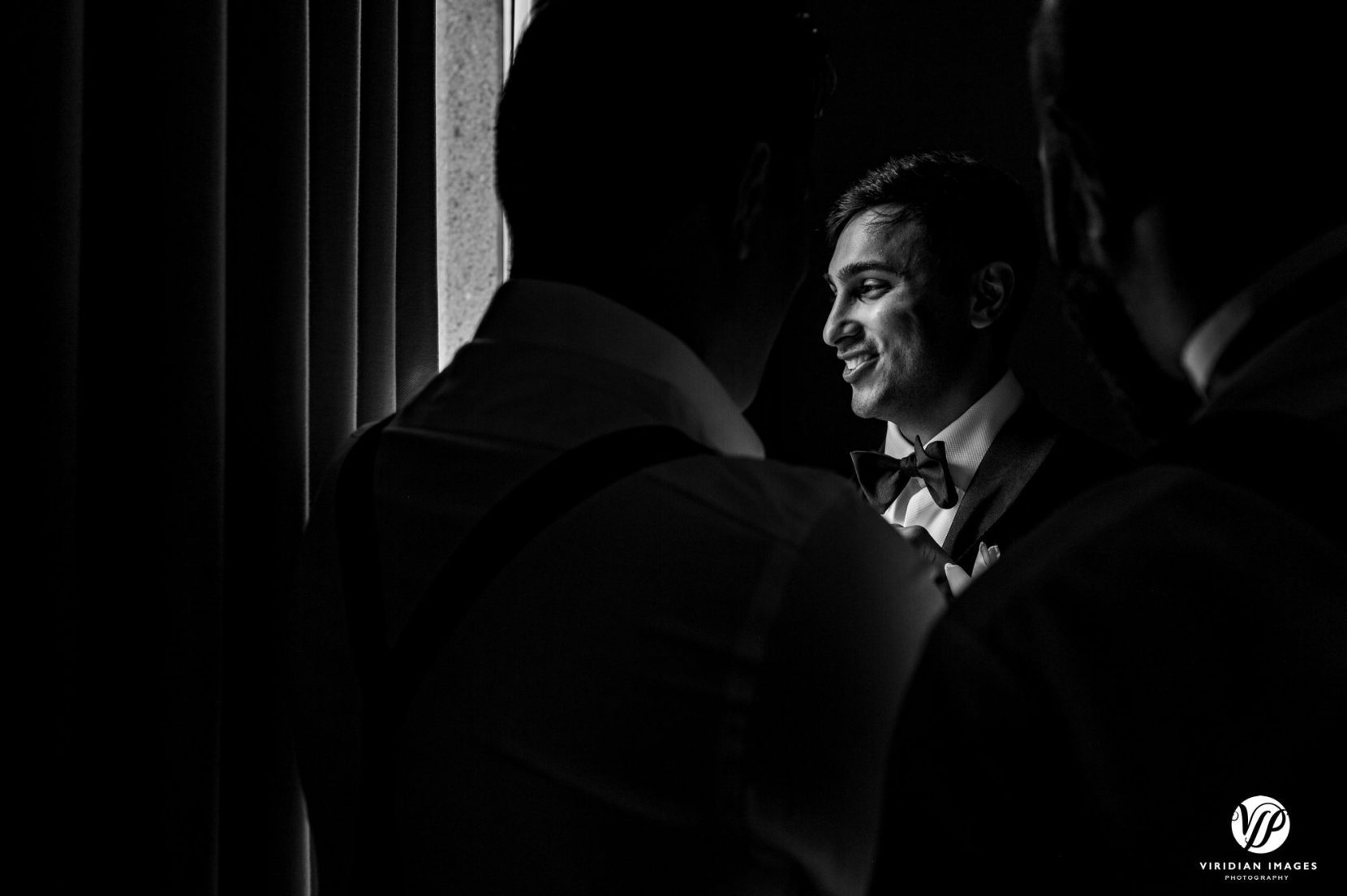 groom looking out window with groomsmen