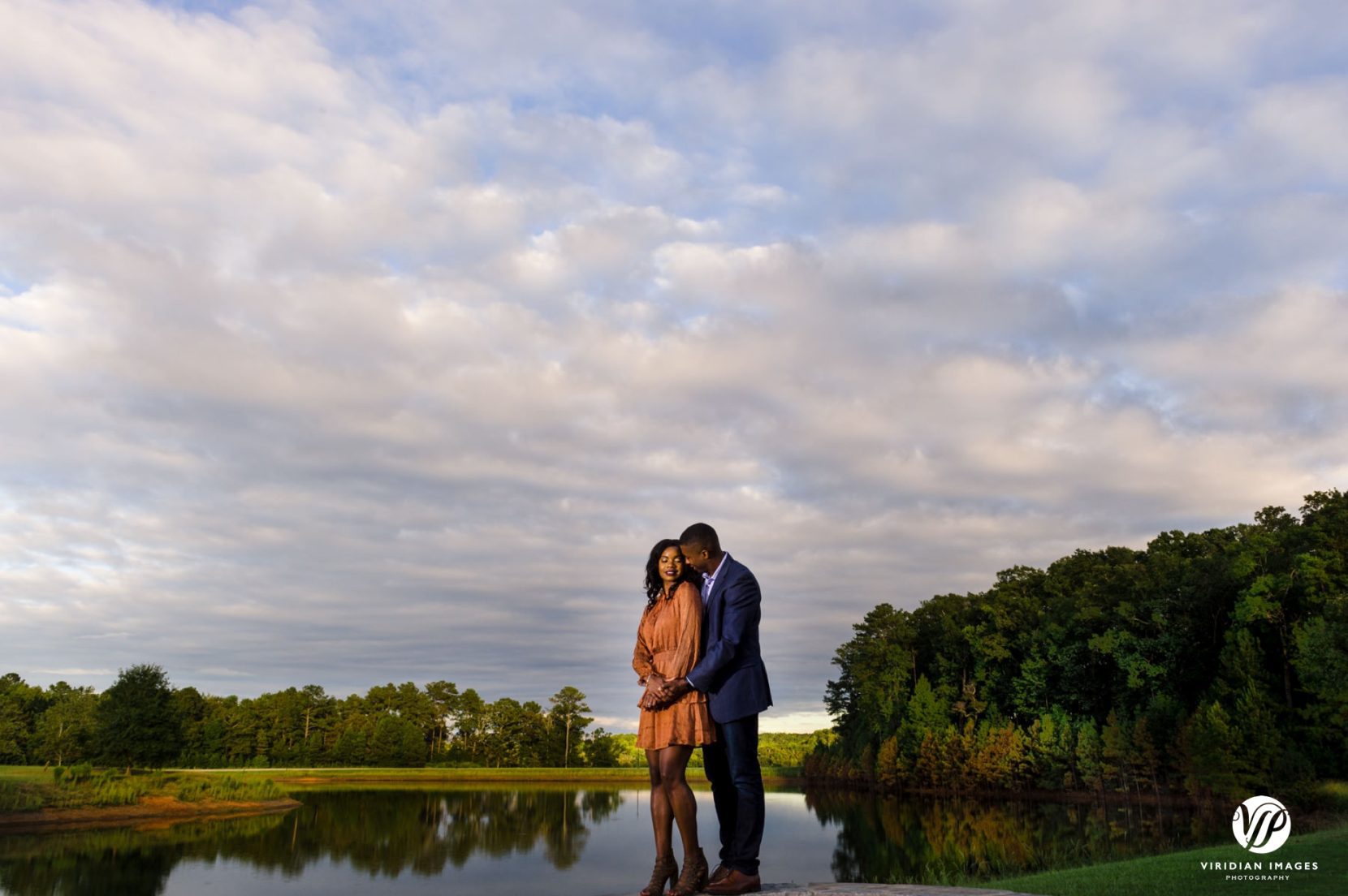couple hugging from behind with expansive white cloud sky backdrop