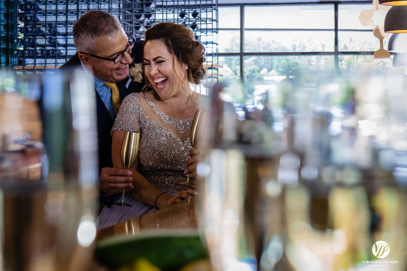 bride and groom creative portrait through wine glasses celebrating each other