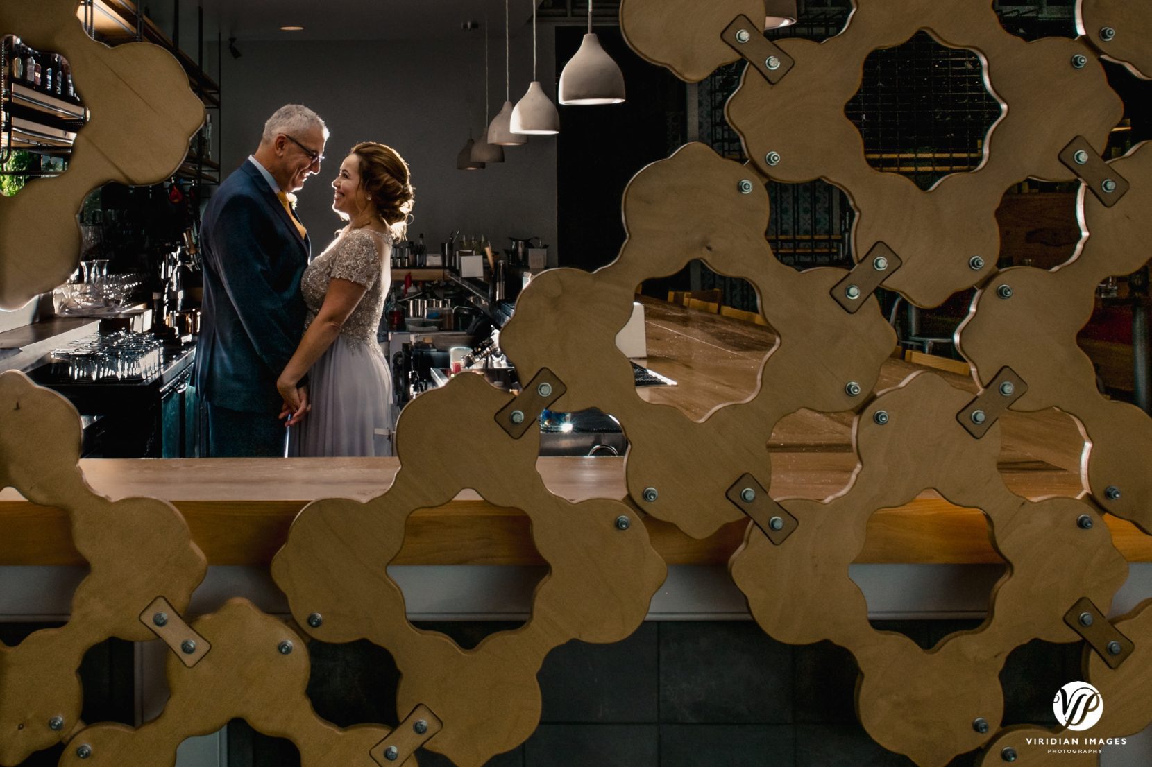 bride and groom portrait behind bar and through wall detail