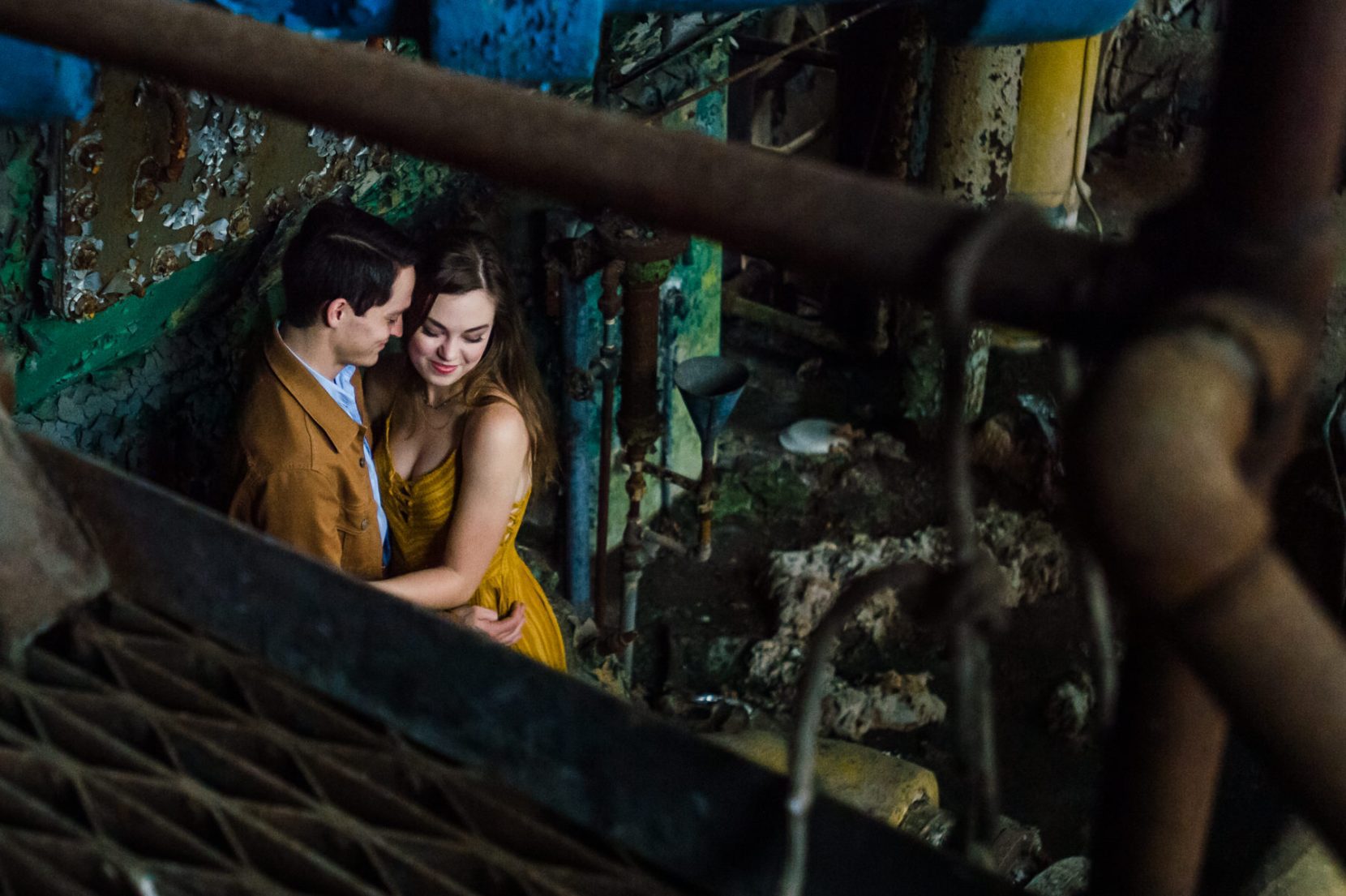 Romantic engagement photo at Lindale Mill with couple embracing between rusty metal bars