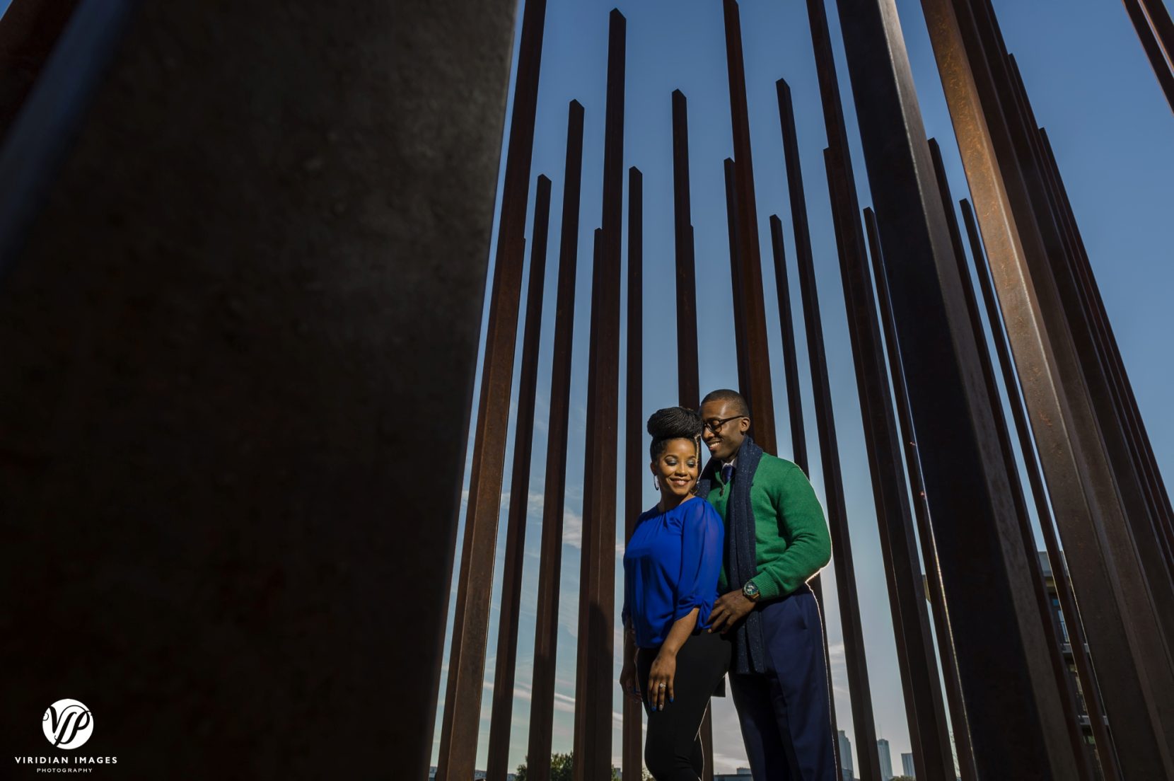 Engaged couple standing in front of iron bars art installation during photoshoot at Atlanta's Beltline