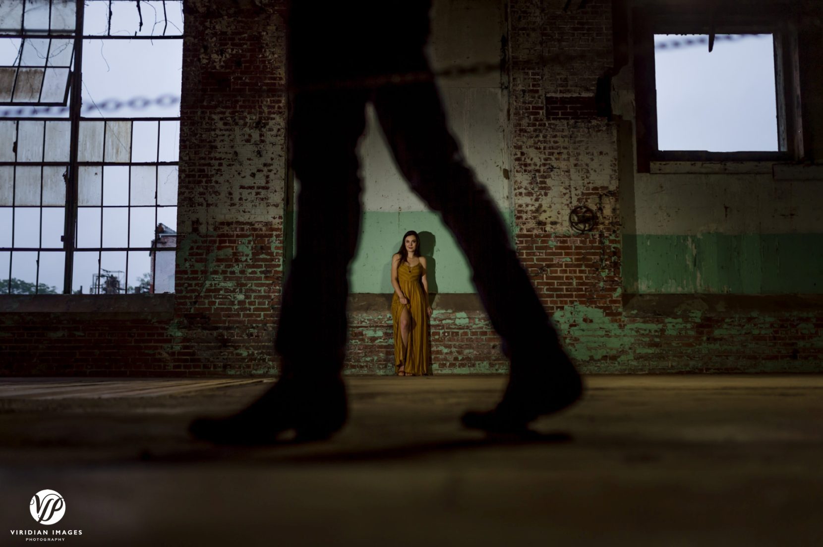 Creative photo of bride between groom's legs at a distance during engagement session at Lindale Mill