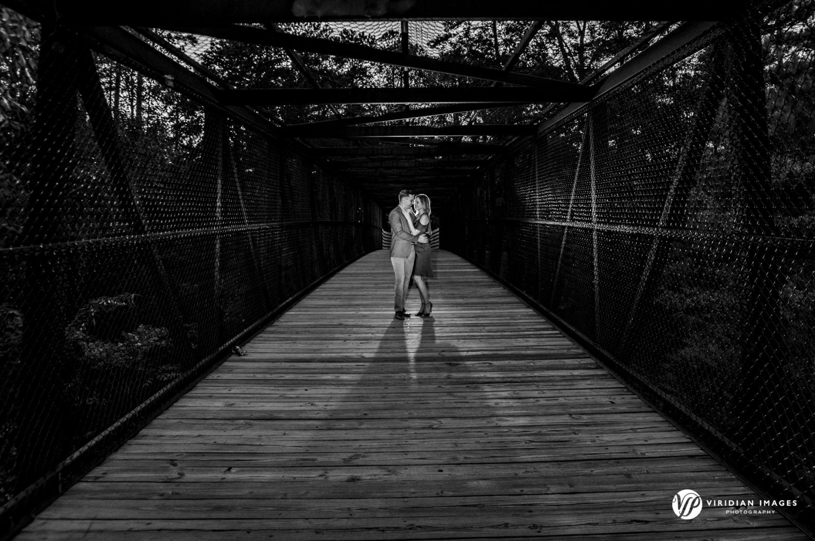 creative, backlit photo of couple center of metal covered bridge for engagement session at mason mill park decatur, georgia photo