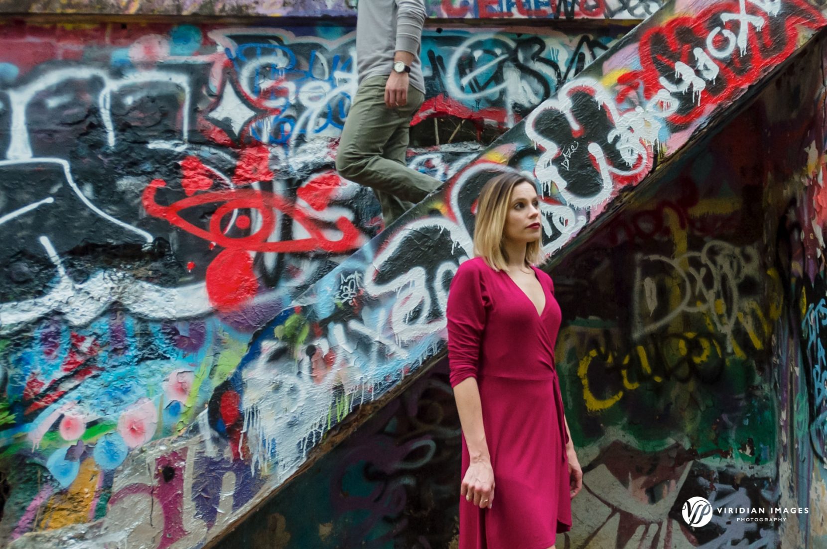 editorial styled image of man walking down the graffiti covered concrete stairs while girl standing along side
