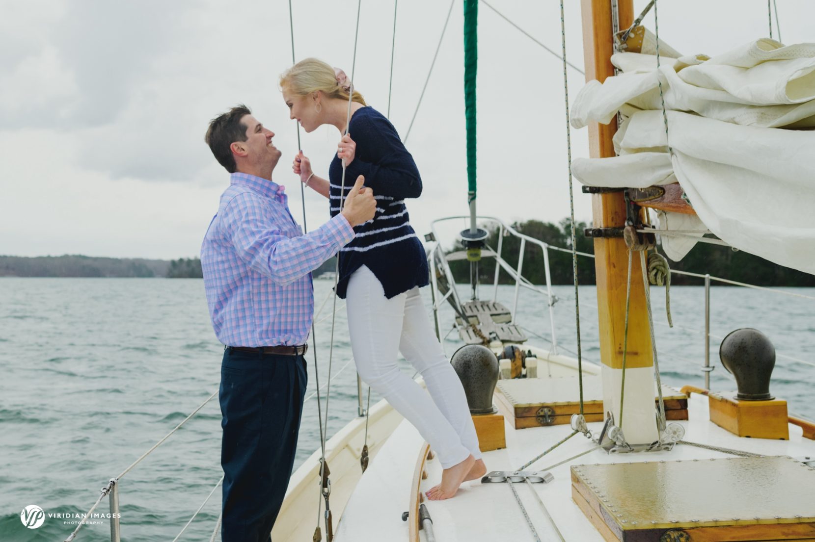 Couple about to kiss on sailboat during engagement session with storm clouds in background