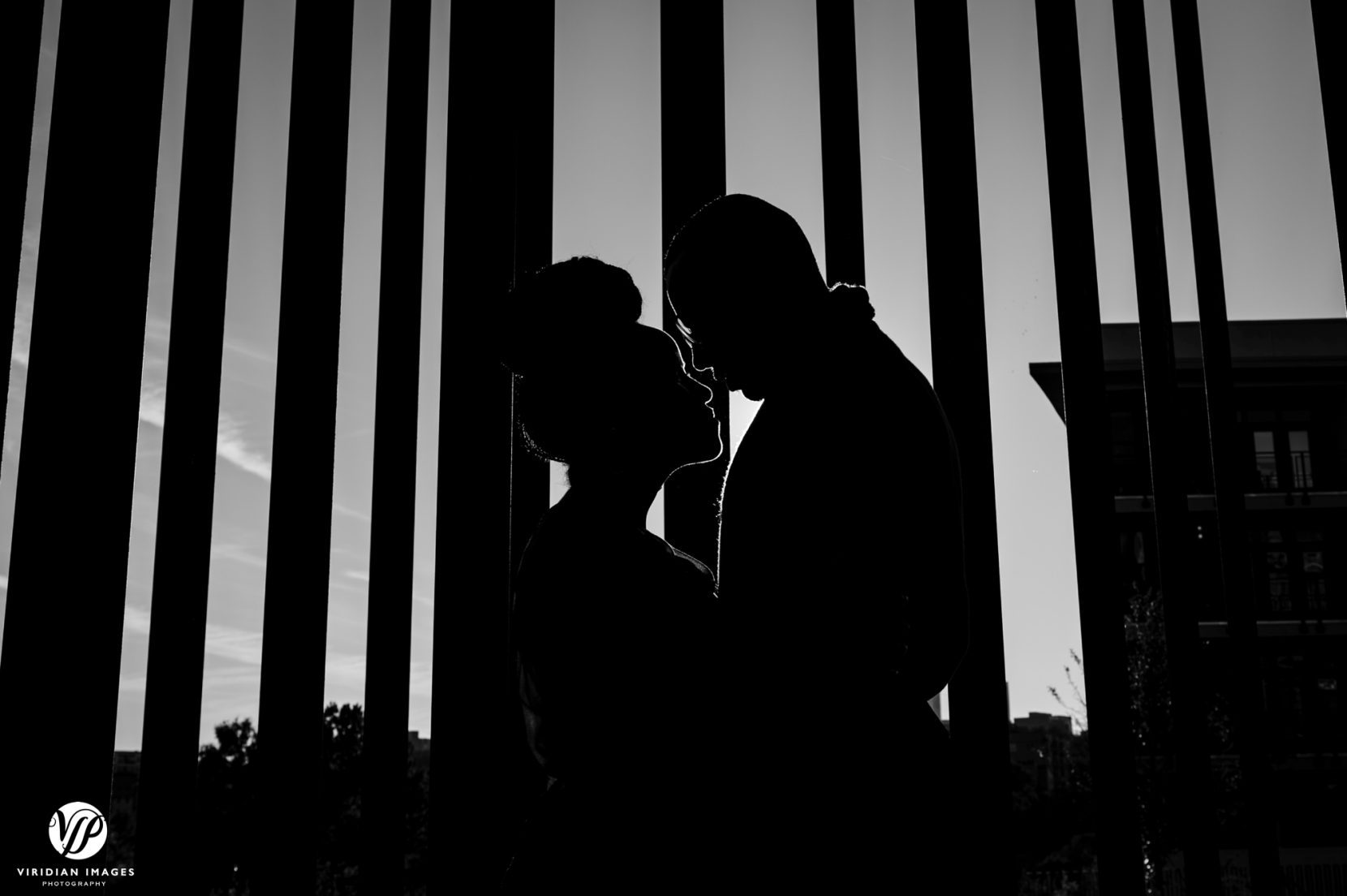 Couple face to face silhouette against art installation and bright sky during engagement session