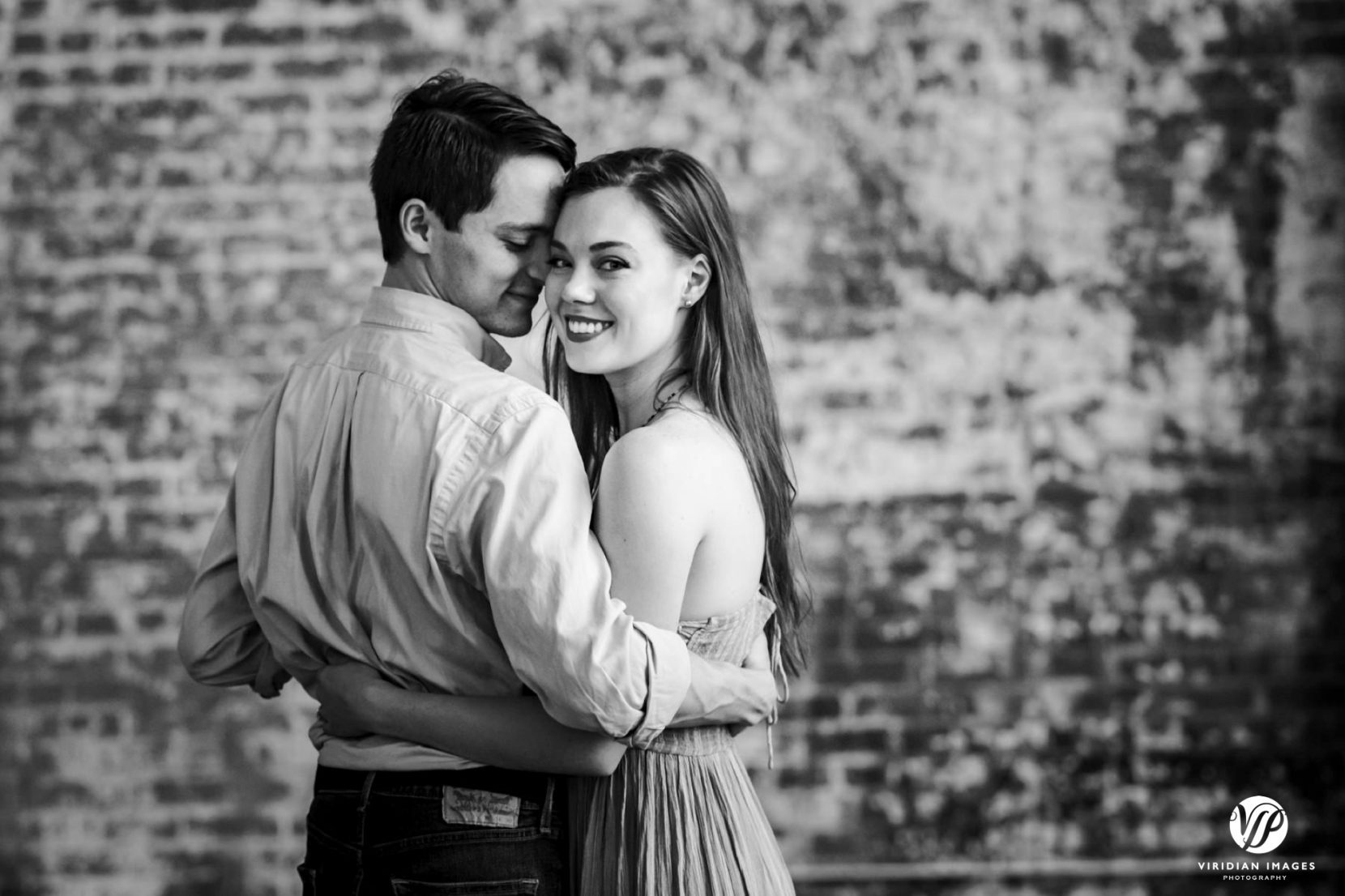 Romantic photo of couple hugging in front of brick wall