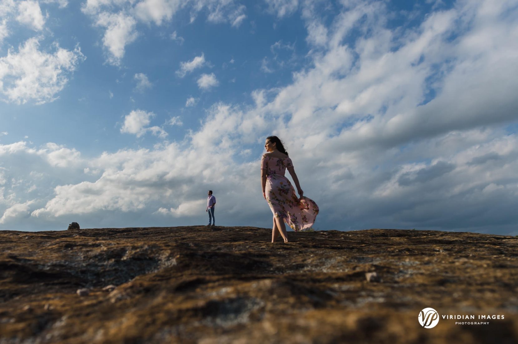 Couple on rocky surface of Arabia Mountain again blue skies during engagement shoot