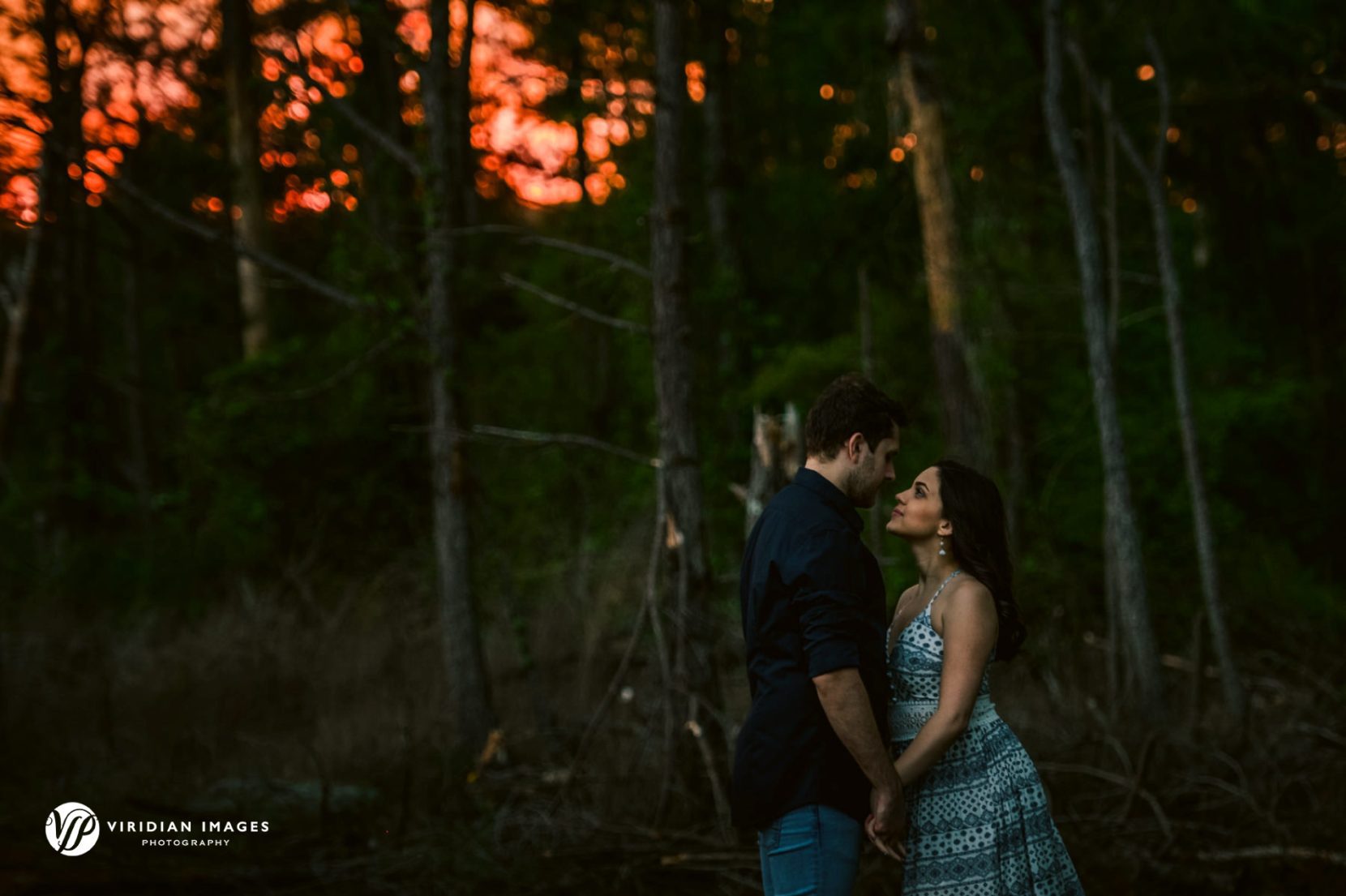 Romantic photo of couple during spring engagement shoot against fiery skies after storm