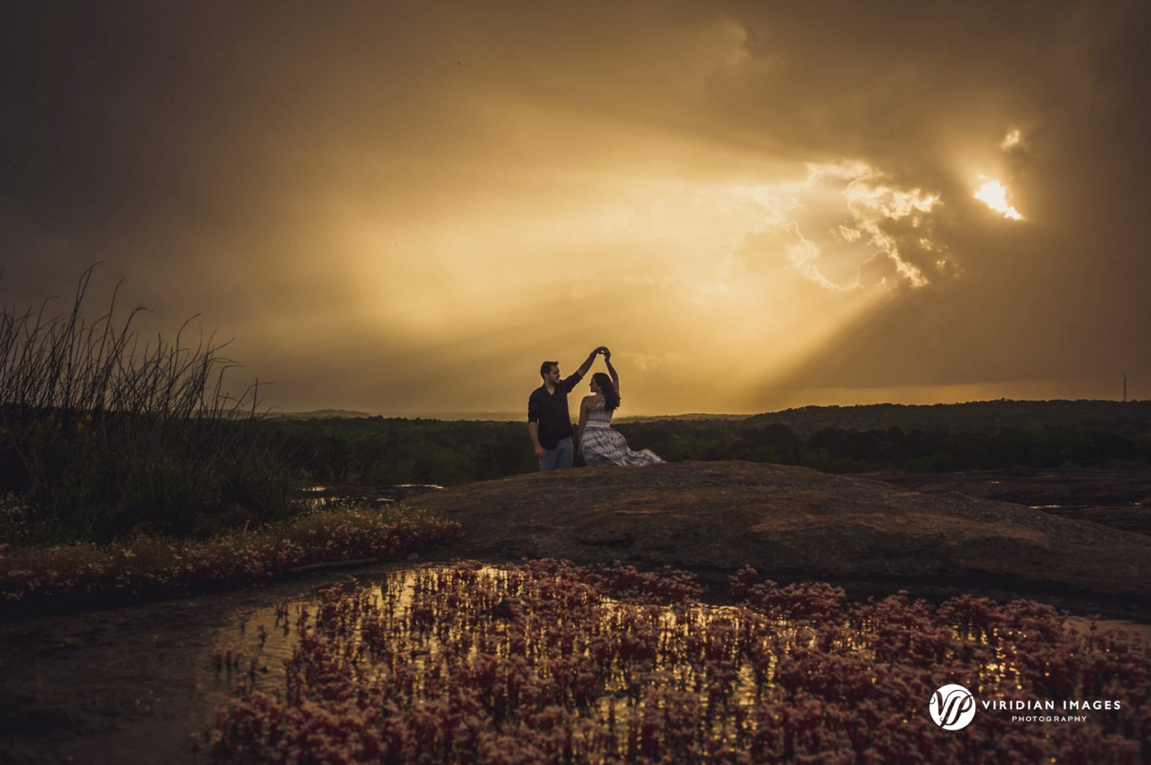 Golden hour sunbeams shinning through storm clouds onto couple during their spring engagement session at Arabia Mountain