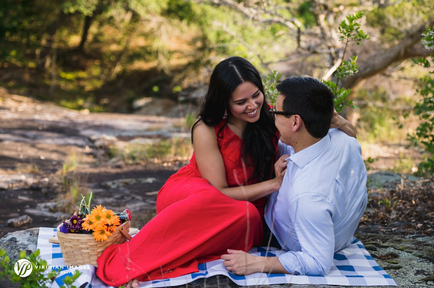 romantic couple on picnic blanket with basket full of flowers and snacks