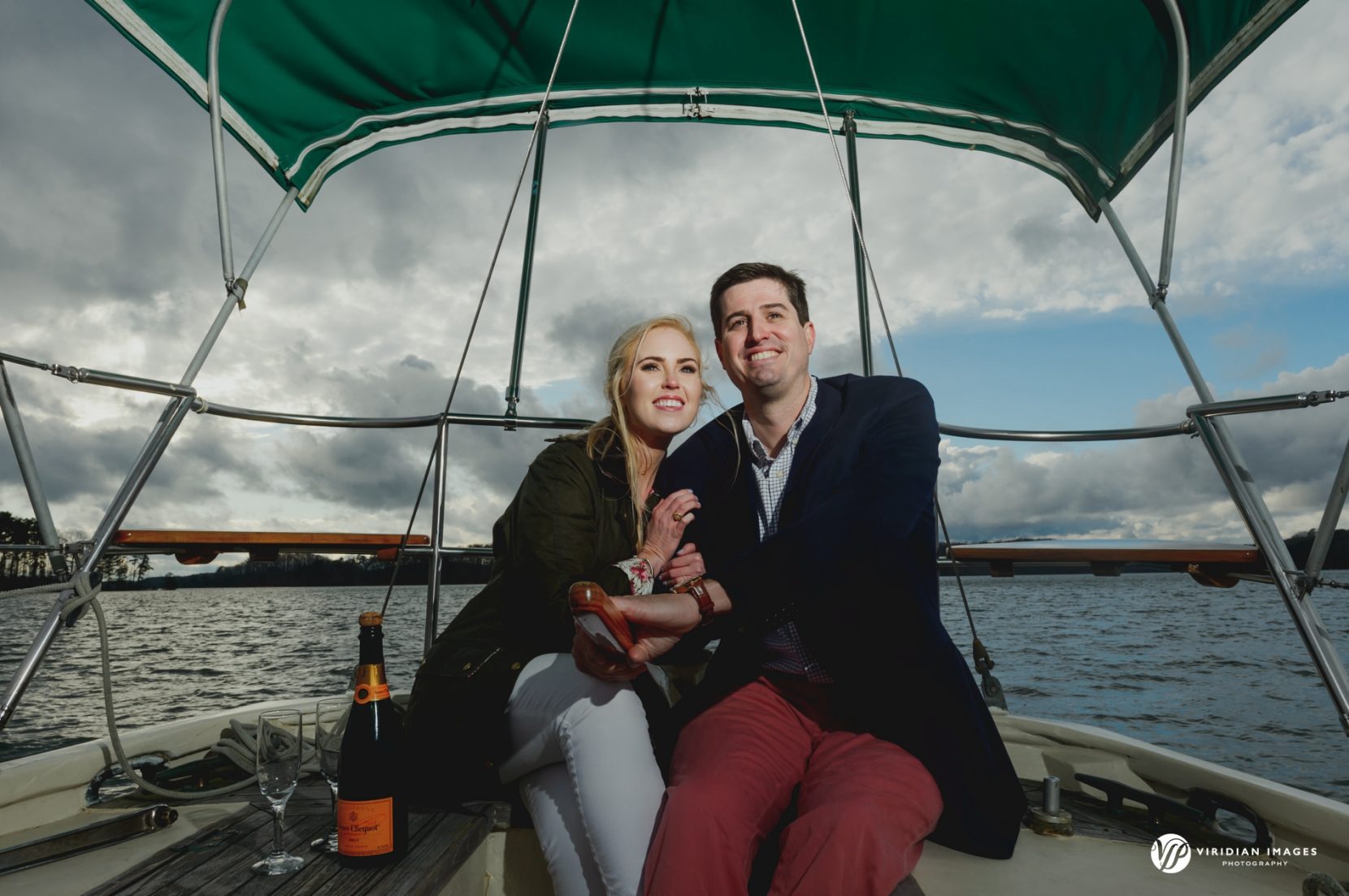 Couple steering boat with champagne as storm clouds roll away in background on lake 
