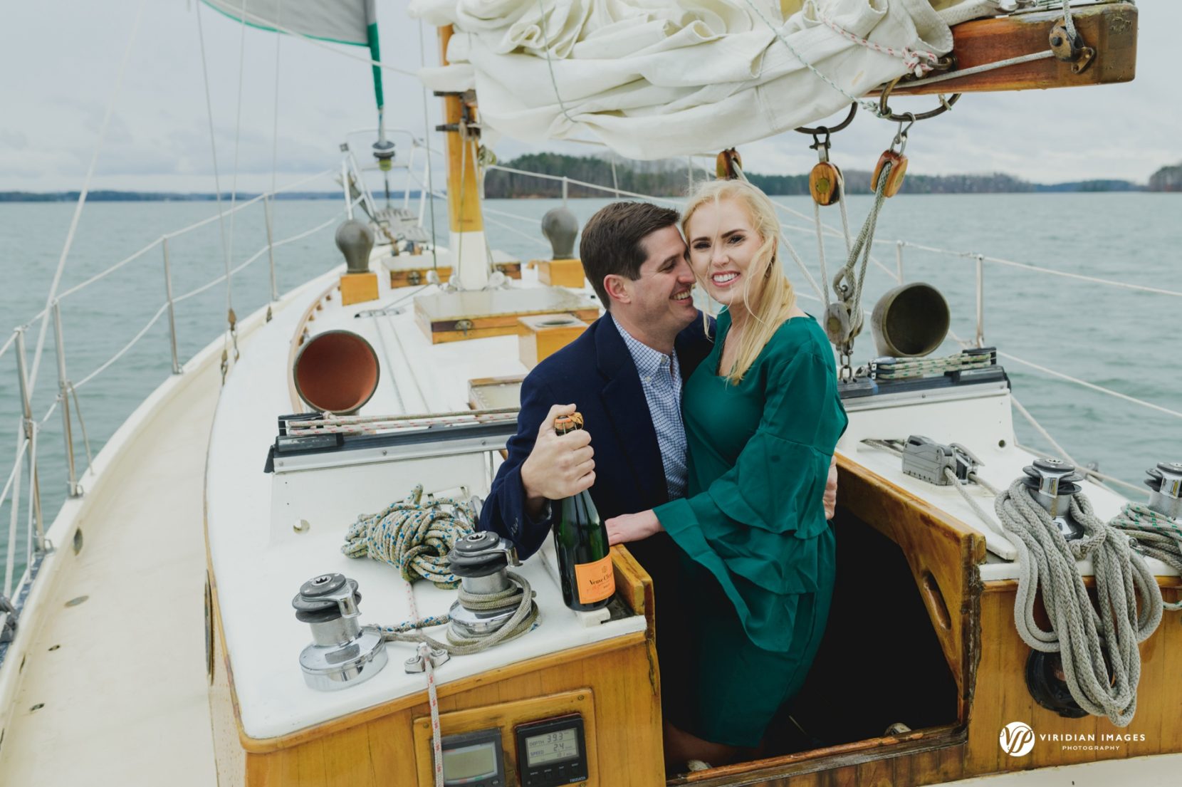 Portrait of couple climbing out below  deck of sailboat on Lake Lanier with champagne
