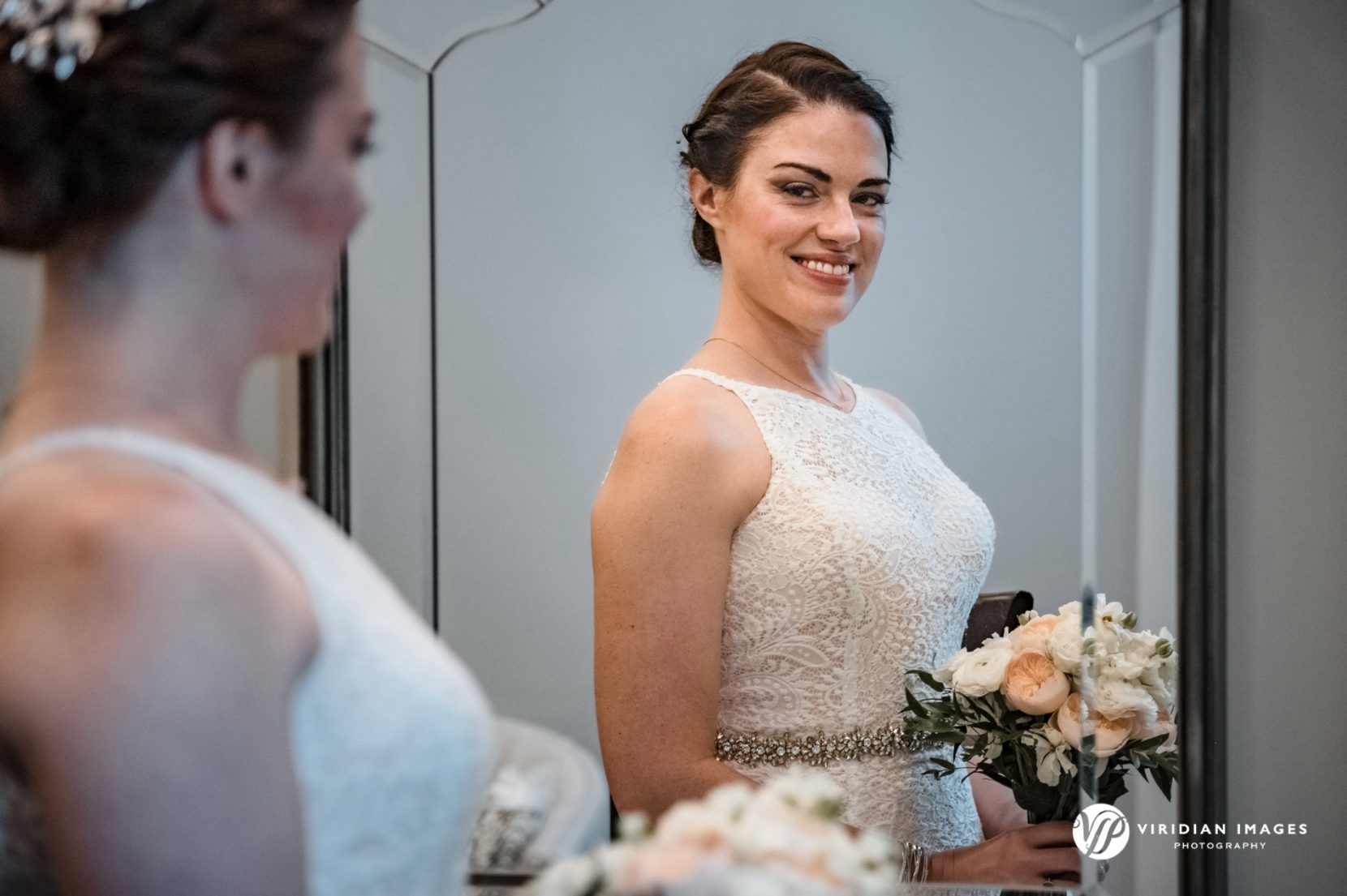 Bride admiring herself in mirror with bouquet right before ceremony