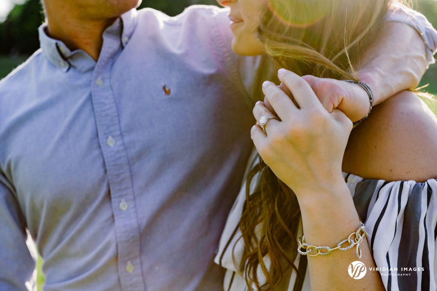 Ring closeup during late afternoon engagement session man with arm over woman