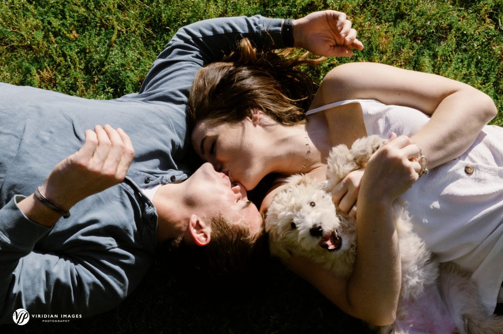 Couple kiss from above and golden doodle looking during Piedmont Park engagement session
