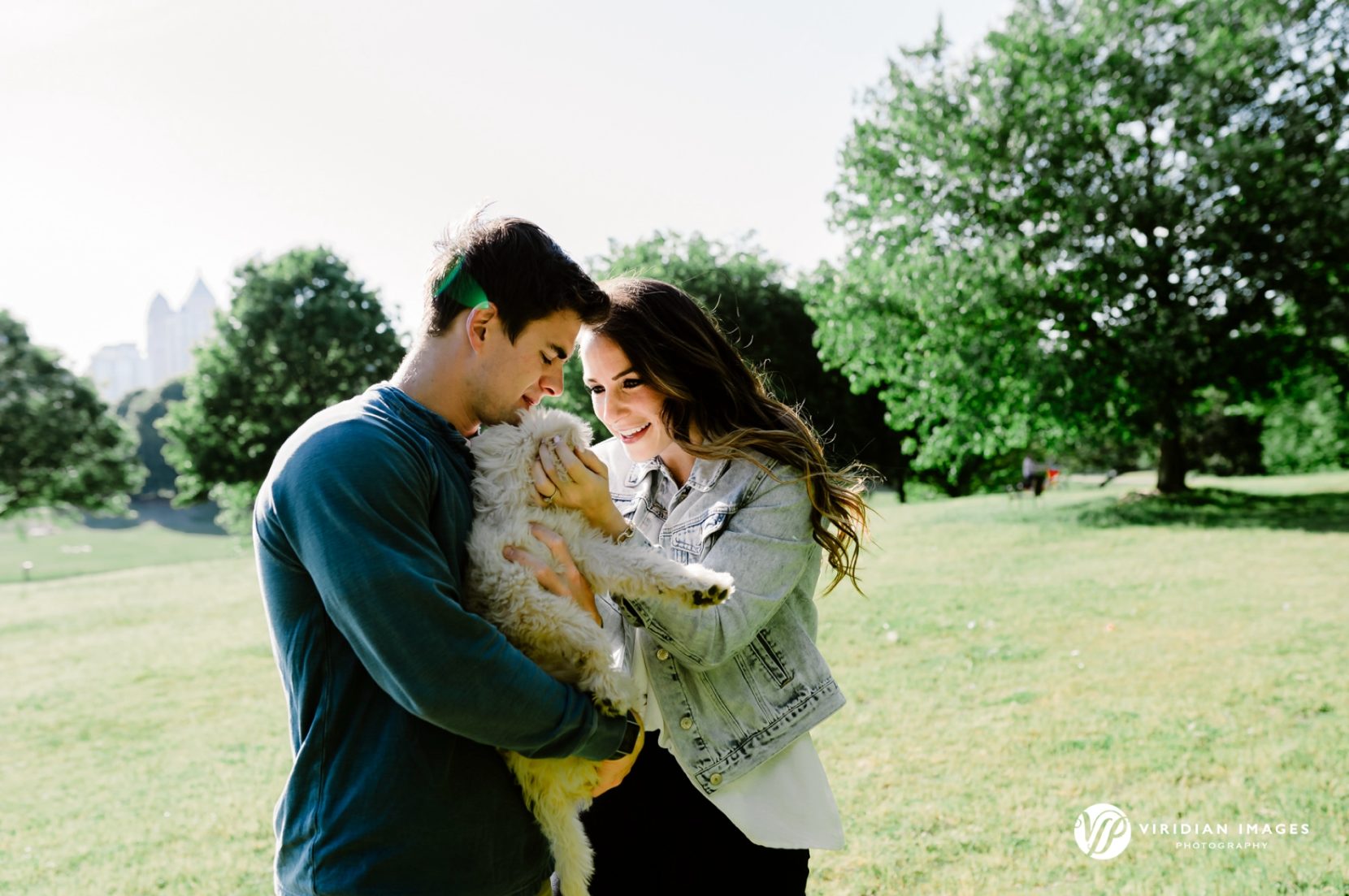 Couple kissing golden doodle puppy during Piedmont Park engagement session