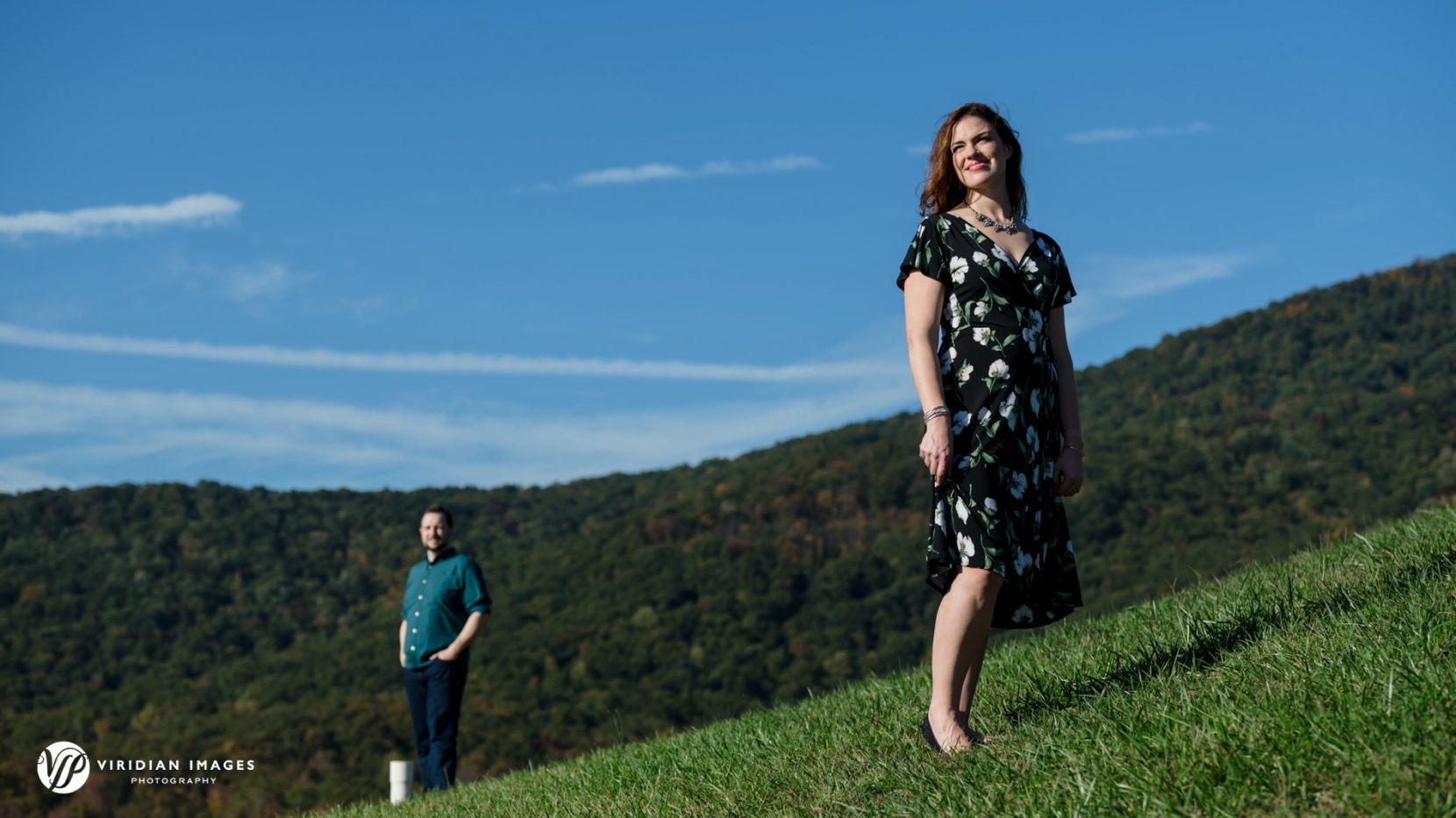 Creative and editorial style engagement session photo with blue skies and mountain ridge