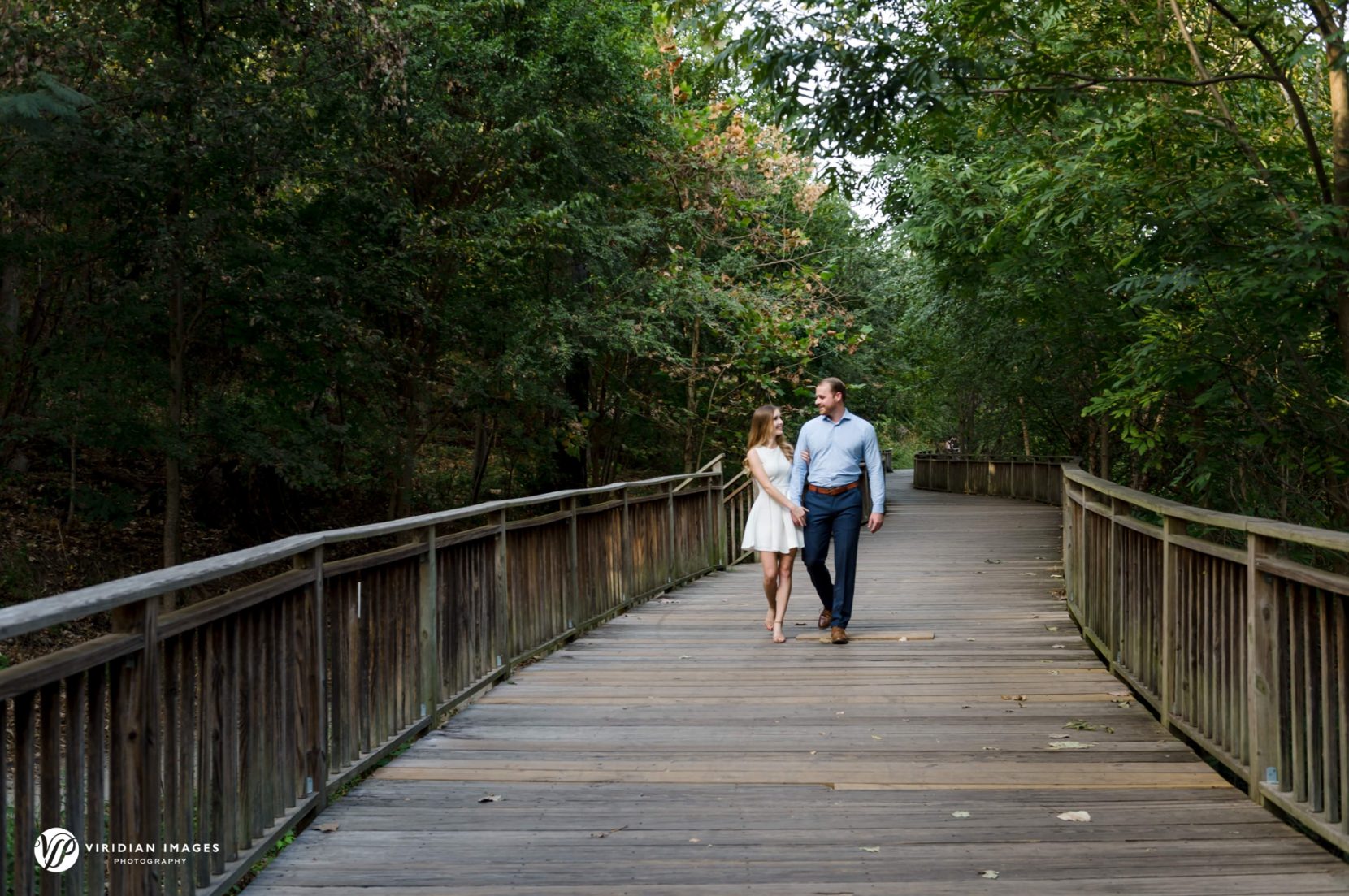 Engaged couple walking hand-in-hand along wood path in Piedmont Park