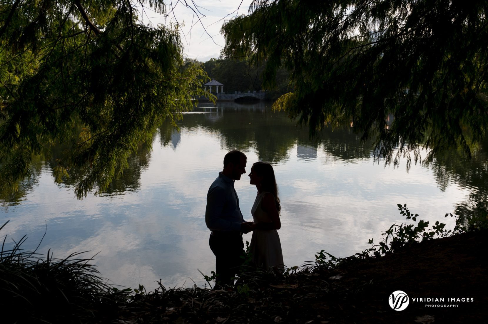 Abbey and Justin sharing a quiet, intimate moment surrounded by trees by lake silhouette