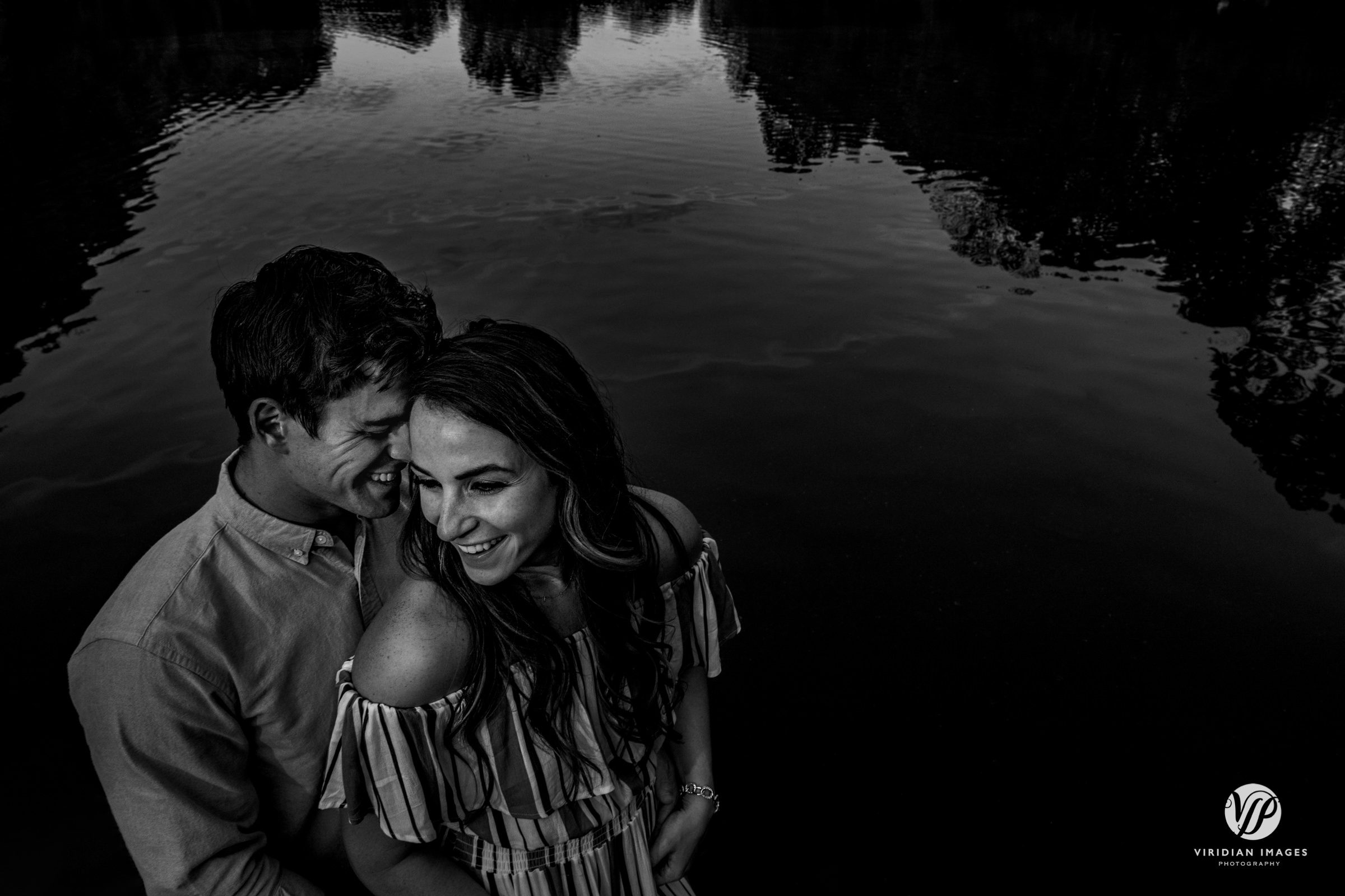 Creative black and white portrait of couple on dock with lake background Piedmont Park engagement