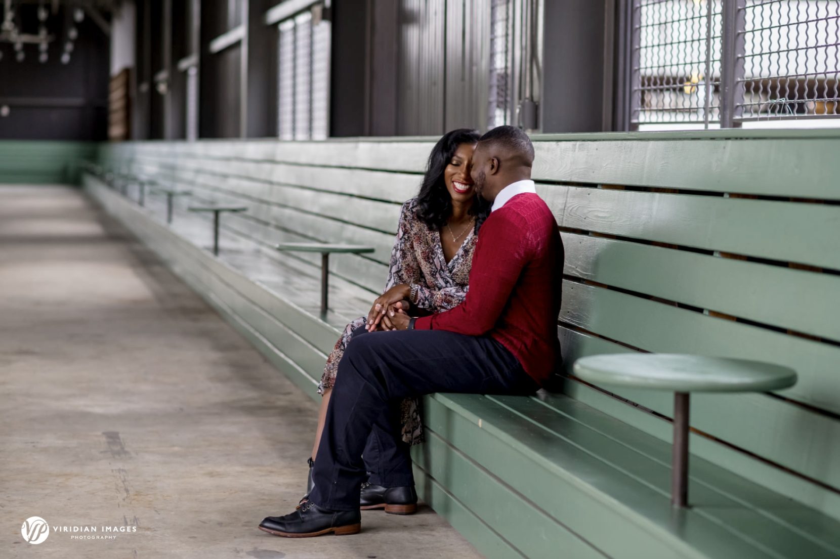 Romantic engagement portrait of couples sitting on green benches at Ponce City Market