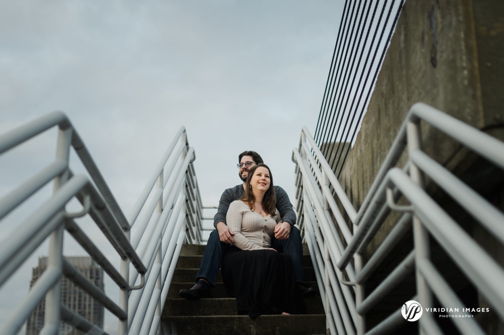 Creative portrait of couple sitting on parking garage stairs against clear sky in downtown Atlanta