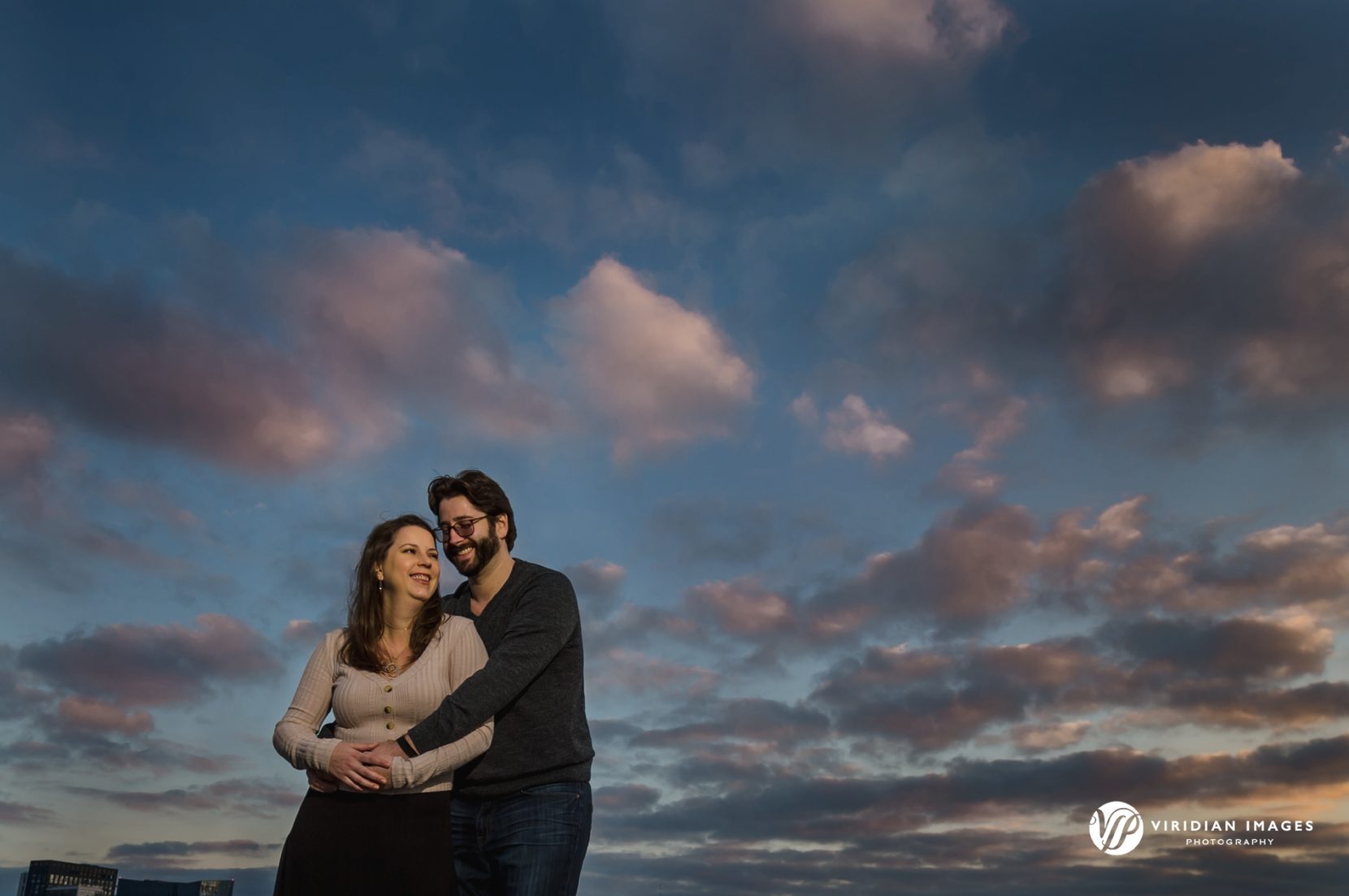 Happy engaged couple against blue skies and clouds during sunset in Atlanta