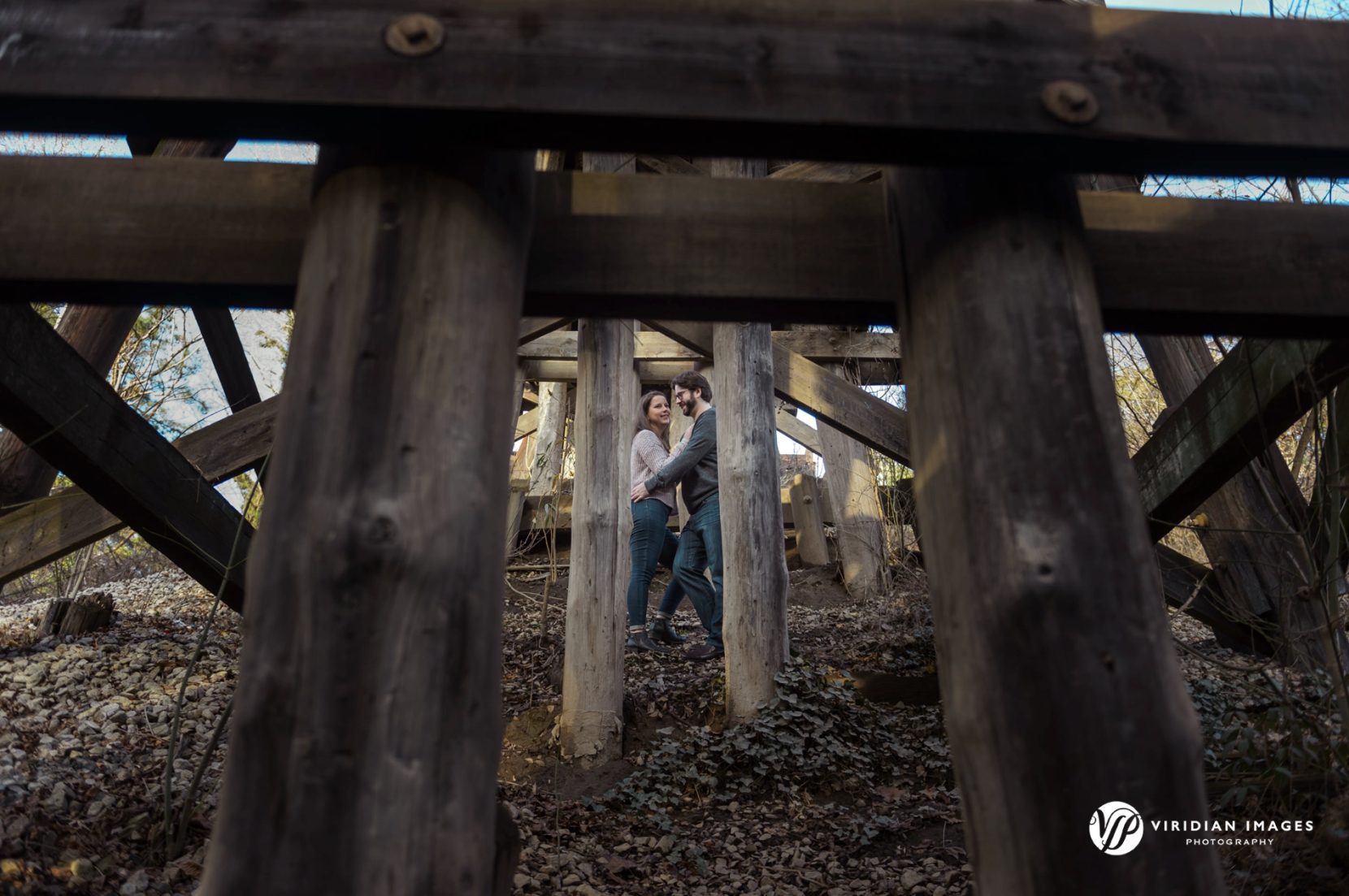 Couple between the wood trestle during engagement session at Tanyard Creek Park