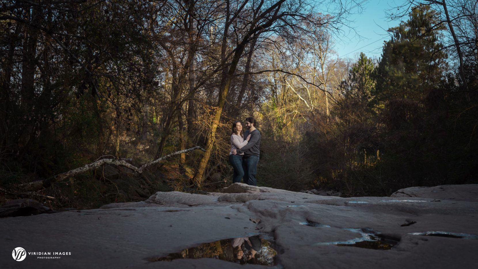 Engaged couple portrait among the trees and river bolder and puddle reflection at Tanyard Creek Park
