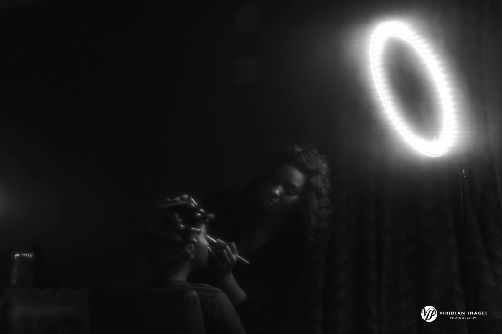 dark and moody creative image of Bride getting make up with ring light