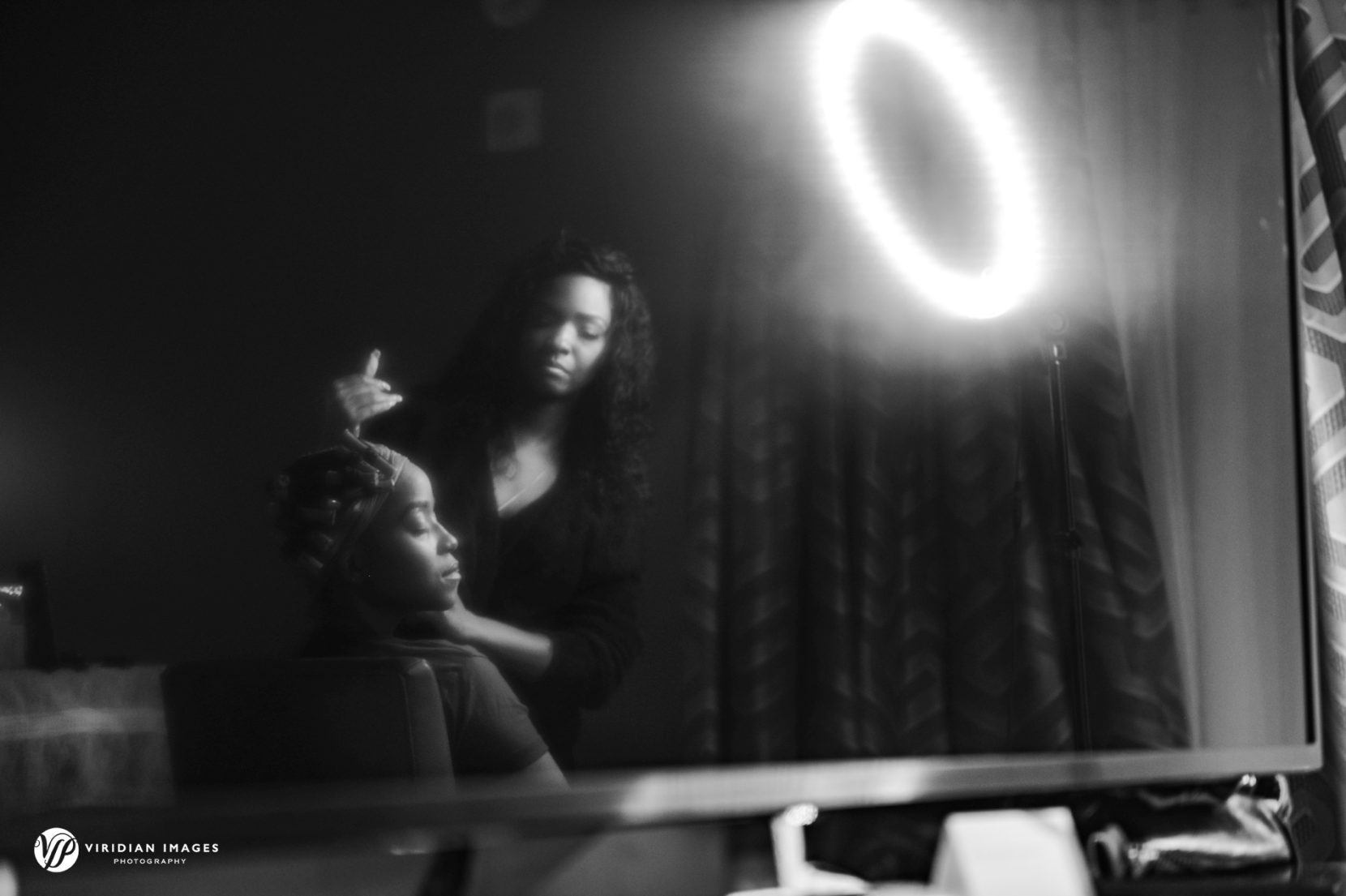dark and moody black and white of bride having make up applied during getting ready