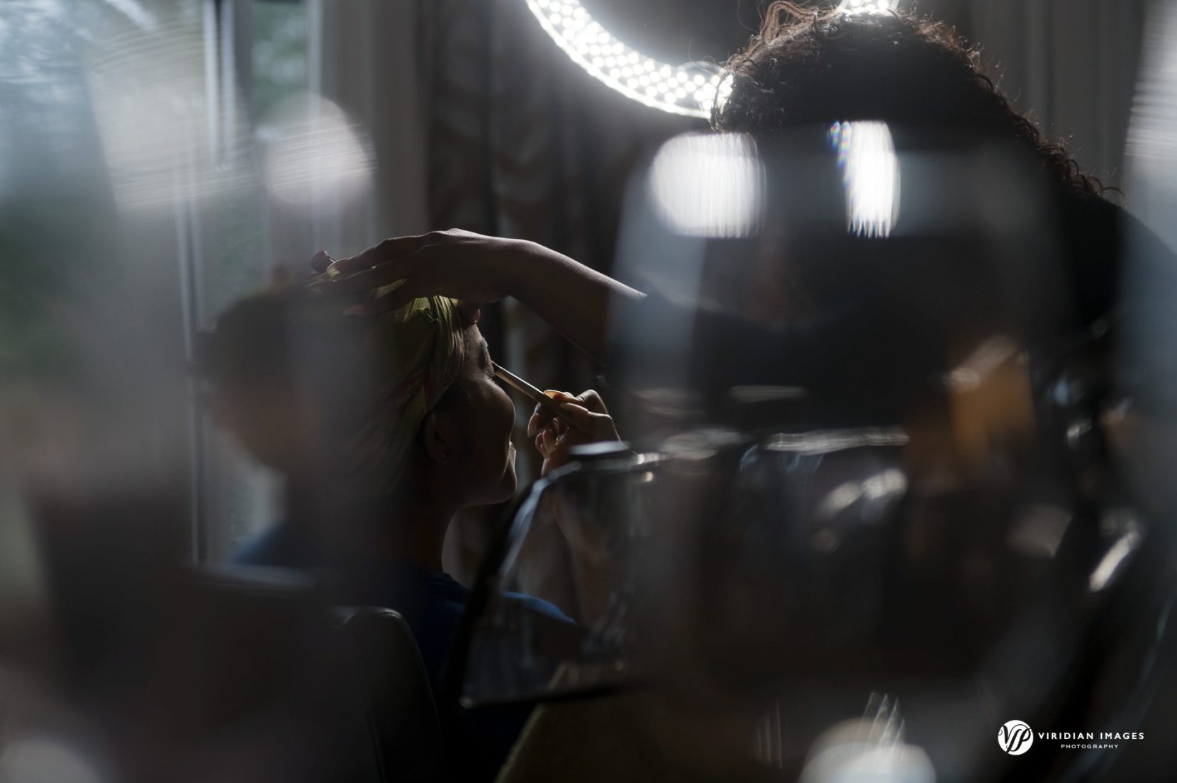 bride captured through glass while getting make up applied at Hyatt Regency Villa Christina Wedding