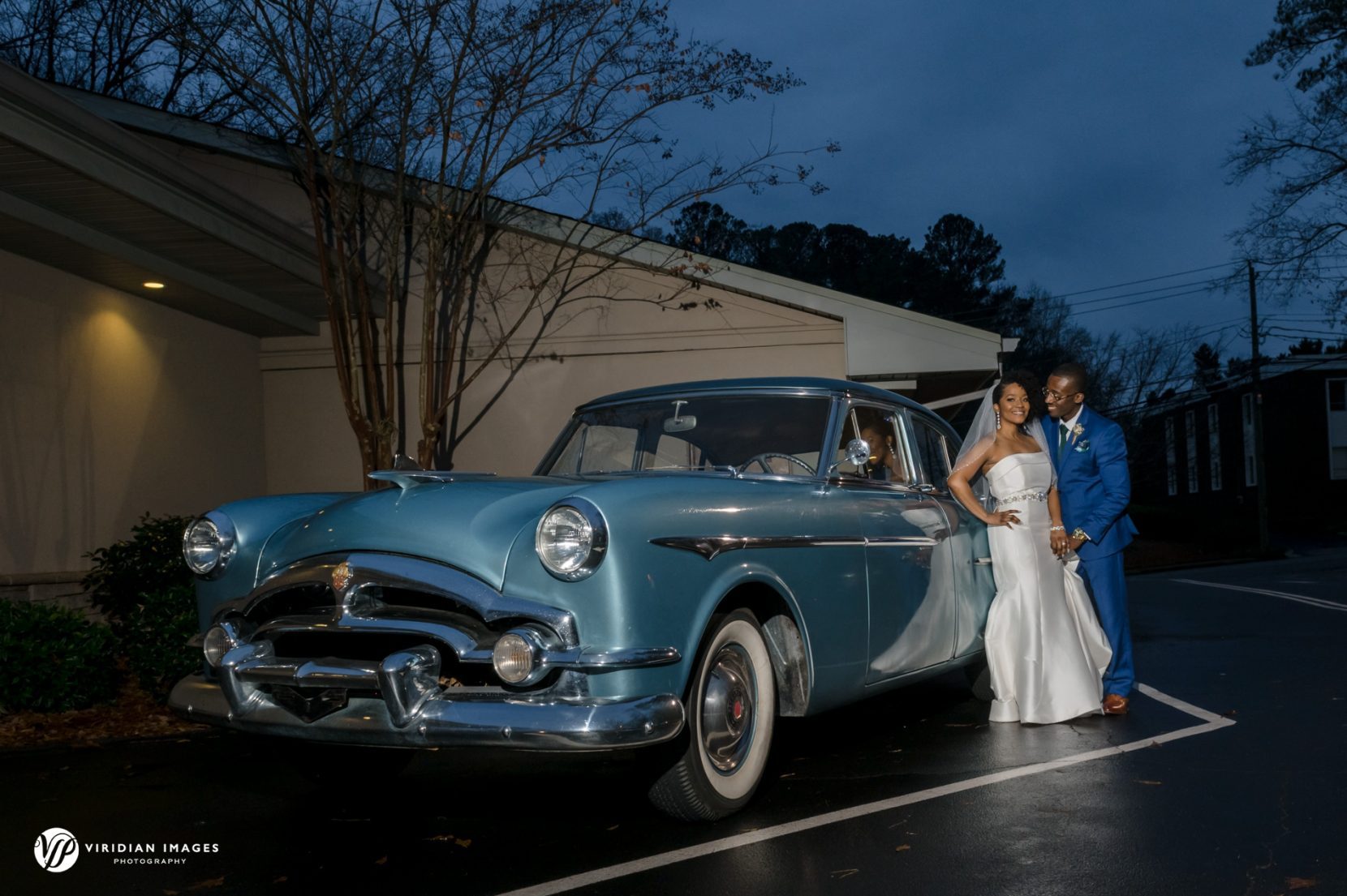 Rainy wedding day portrait outside Kingdom Hall of Jehovah's Witnesses with classic car