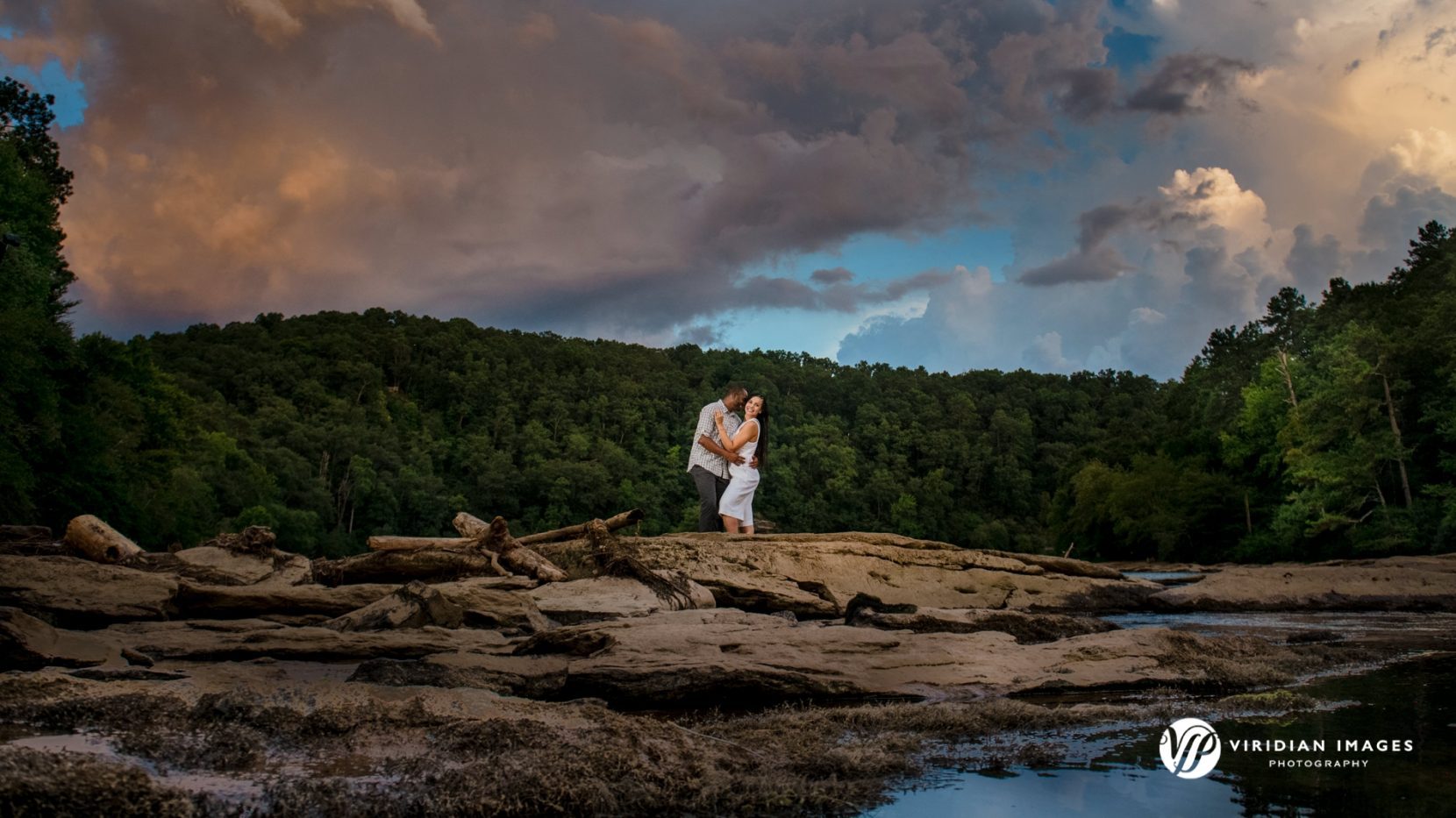 Wide shot of sweet kiss standing on rocks from river at East Palisades Trail