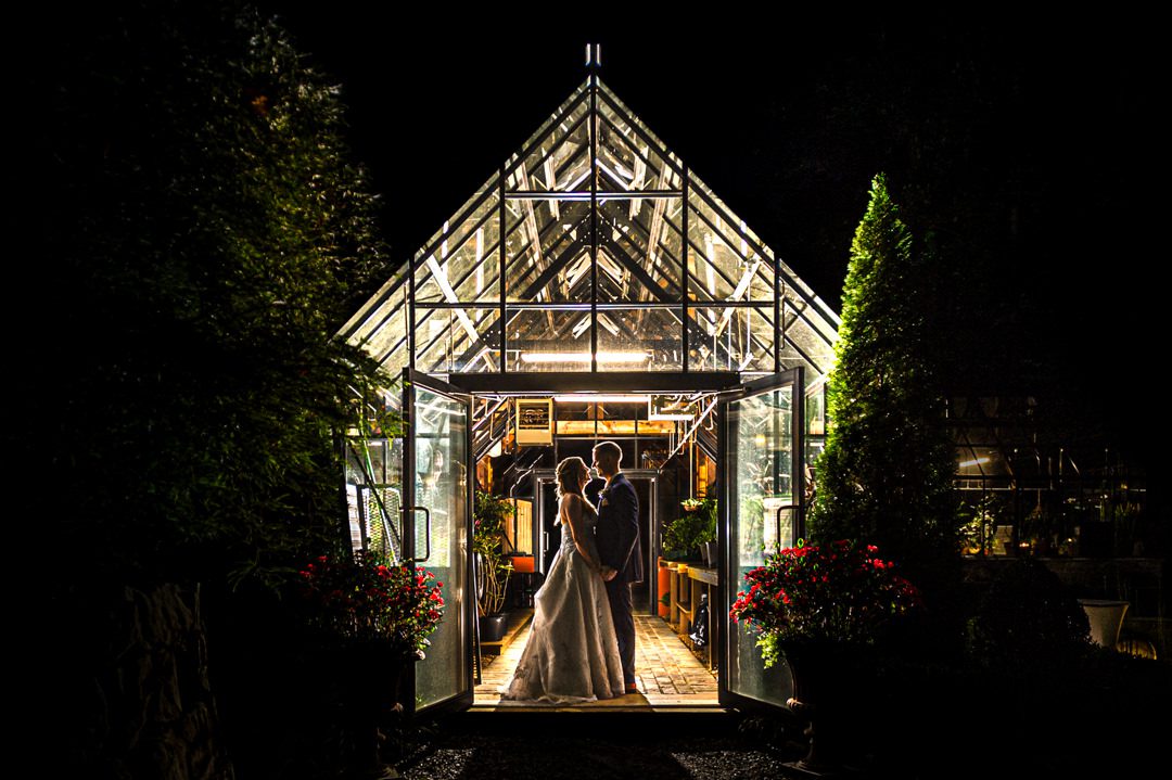 wedding couple silhouette against backlit greenhouse at the end of the night