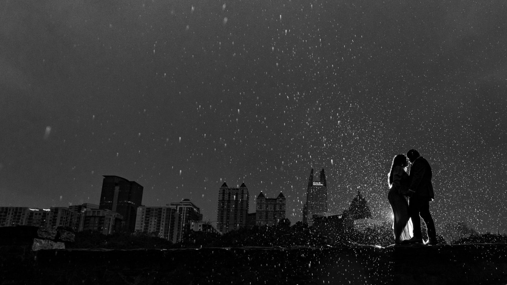 Raindrops highlighted around couple against city skyline