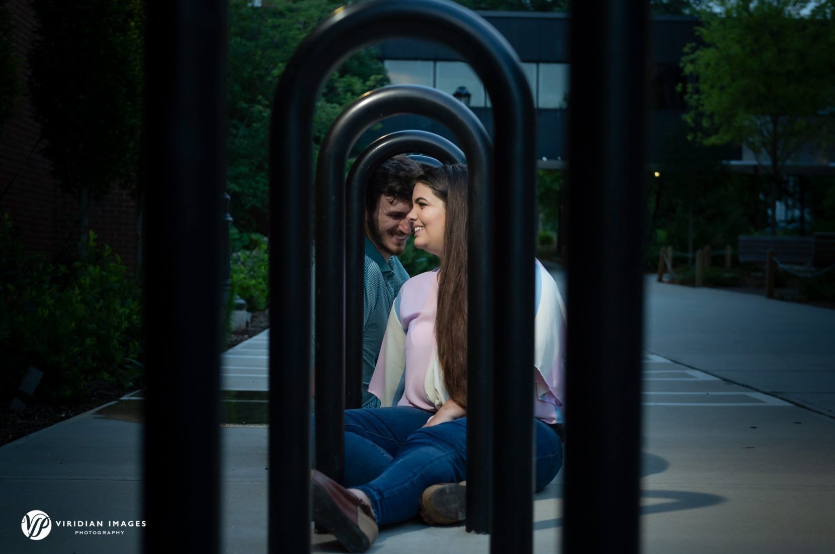 Creative view of engaged couple through curved bike racks at UGA north campus Athens